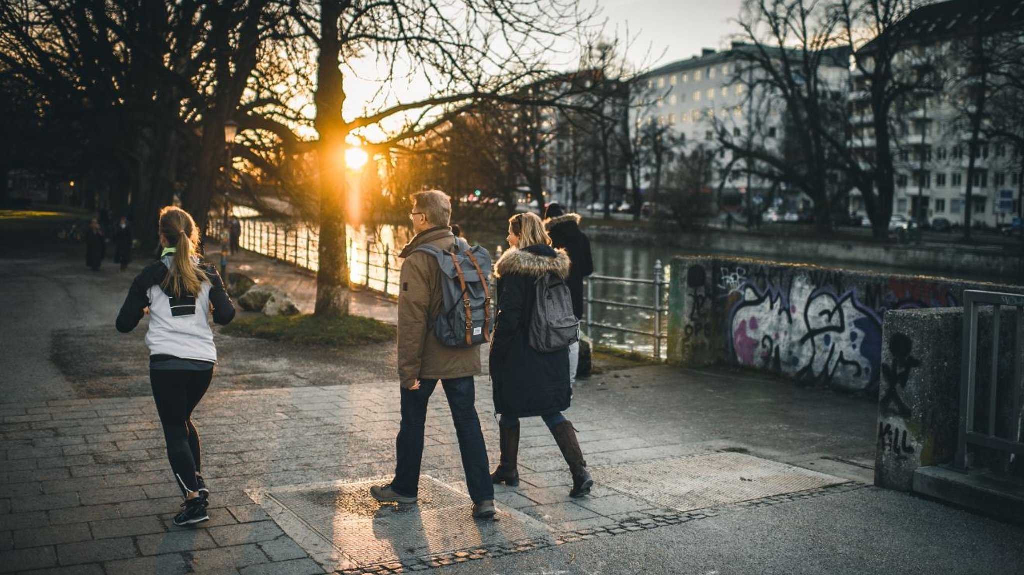 Passantinnen und Passanten laufen an der Isar in München entlang.