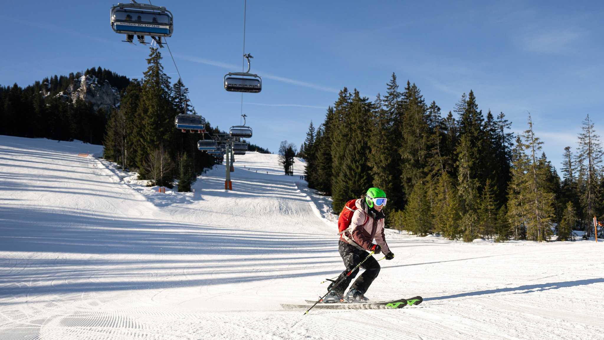 Eine Skifahrerin mit schwarzer Skihose, neongrünem Helm und Rucksack rast in Garmisch-Partenkirchen über die Piste.
