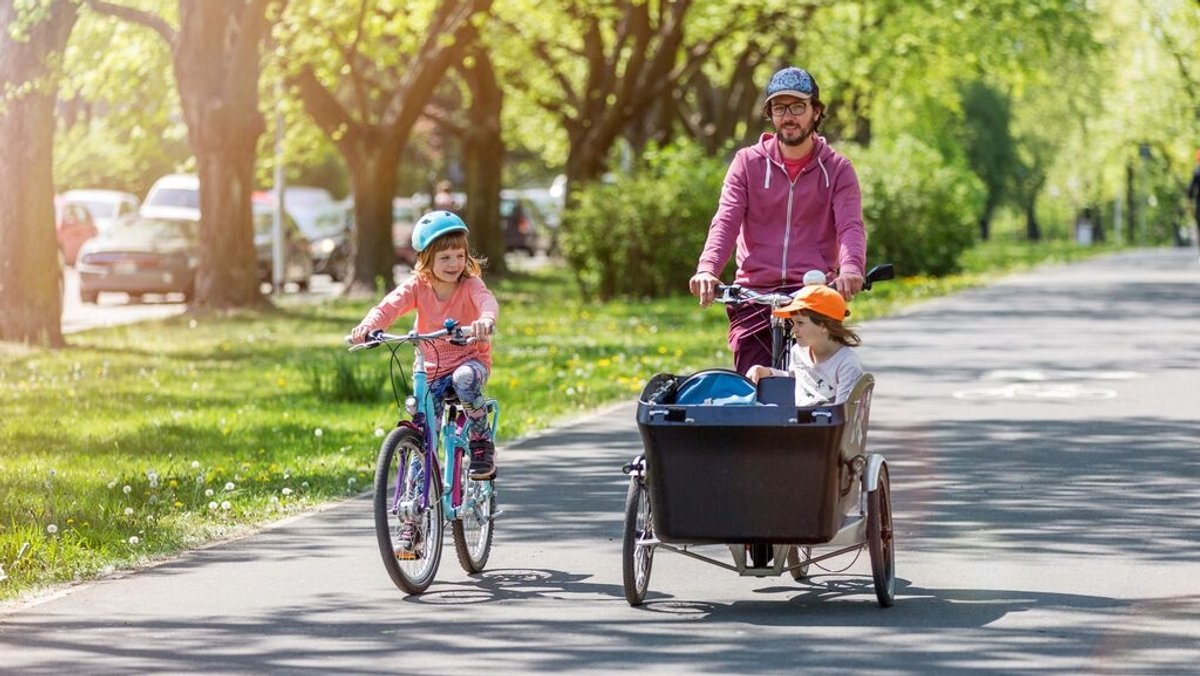 Ein Vater fährt mit seinen Töchtern Fahrrad.