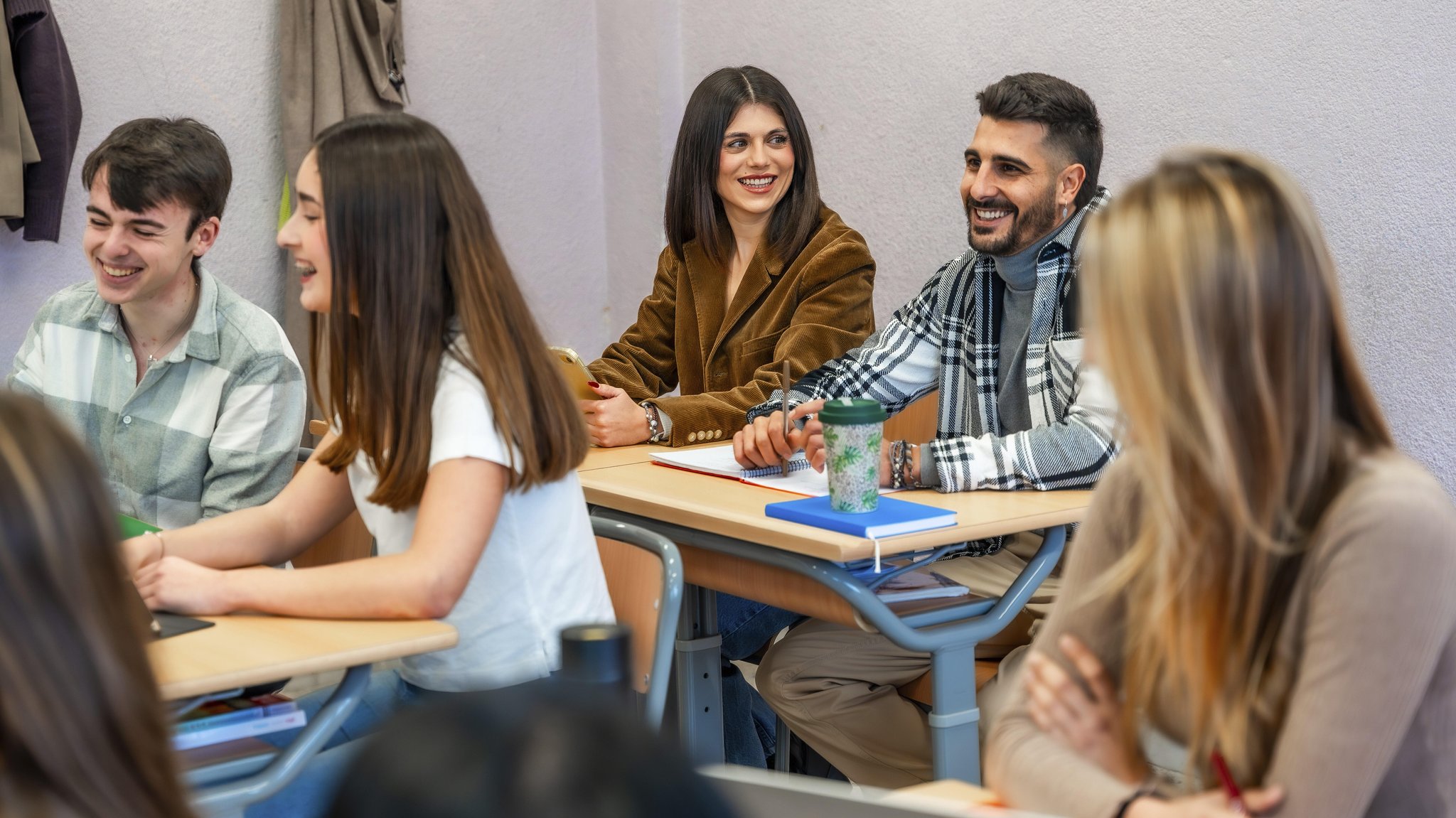 Junge Menschen sitzen gut gelaunt an Tischen in einem Klassenraum. | Bild: dpa/picture-alliance/imageBROKER/Unai Huizi Junge Menschen sitzen gut gelaunt an Tischen in einem Klassenraum.