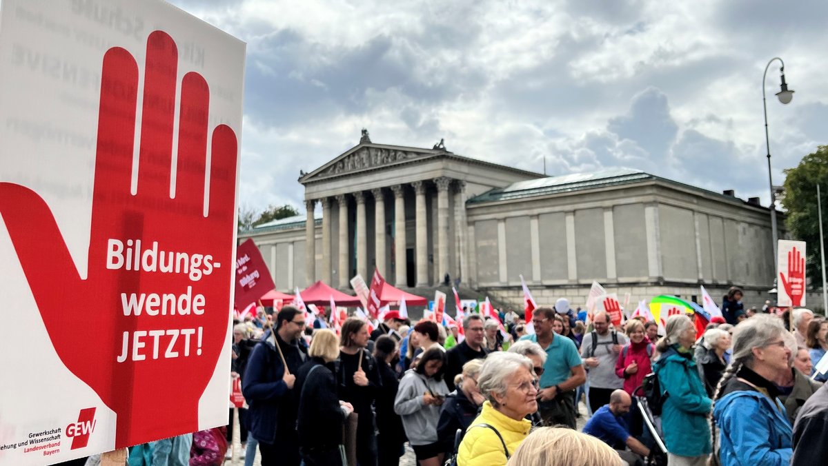 Protestierende stehen mit Schildern auf dem Münchner Königsplatz. Auf einem Schild ist "Bildungswende jetzt!" zu lesen.