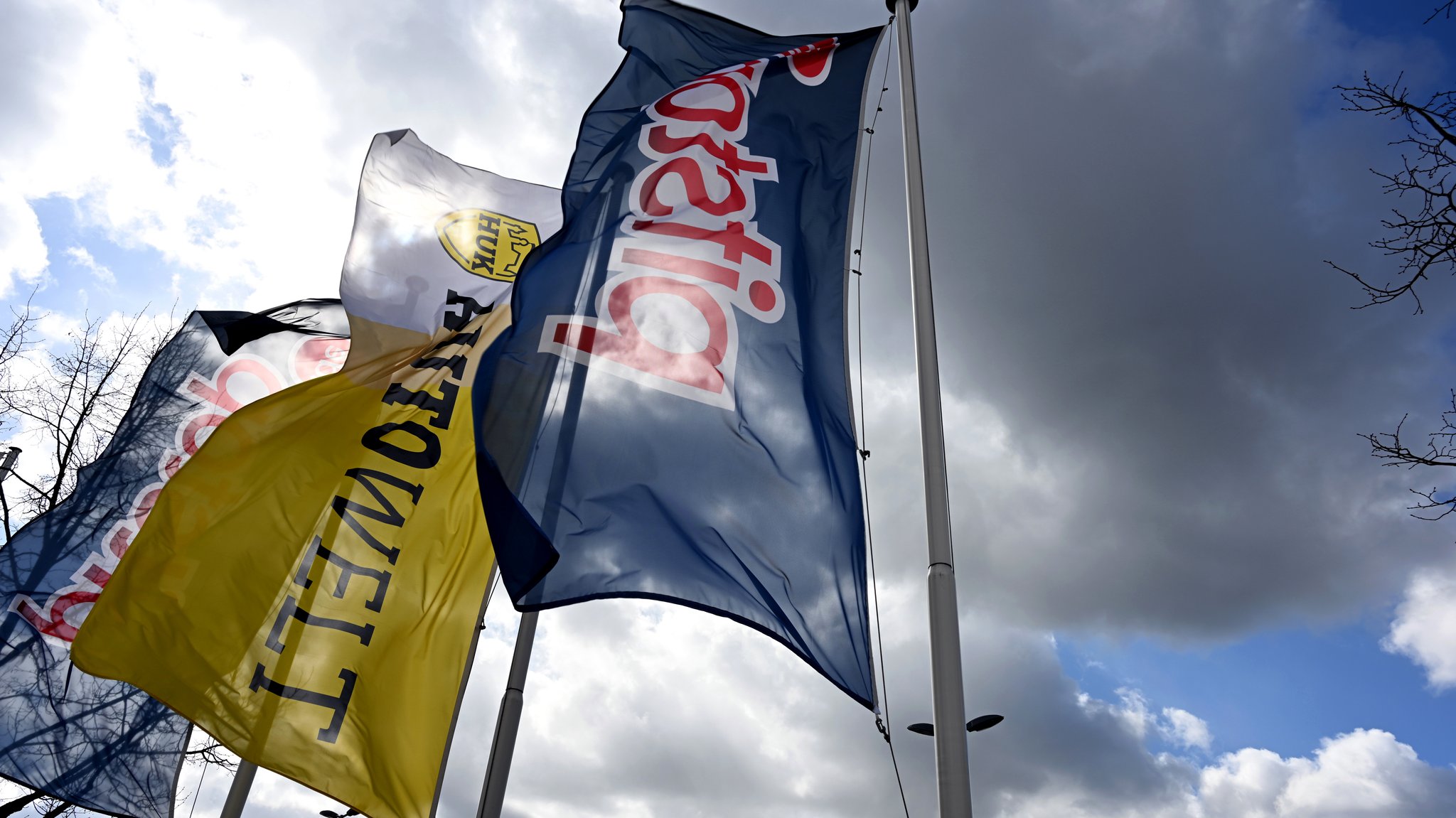 Fahnen der HUK Coburg Autowelt und der Werkstattkette Pitstop wehen nebeneinander im Wind.