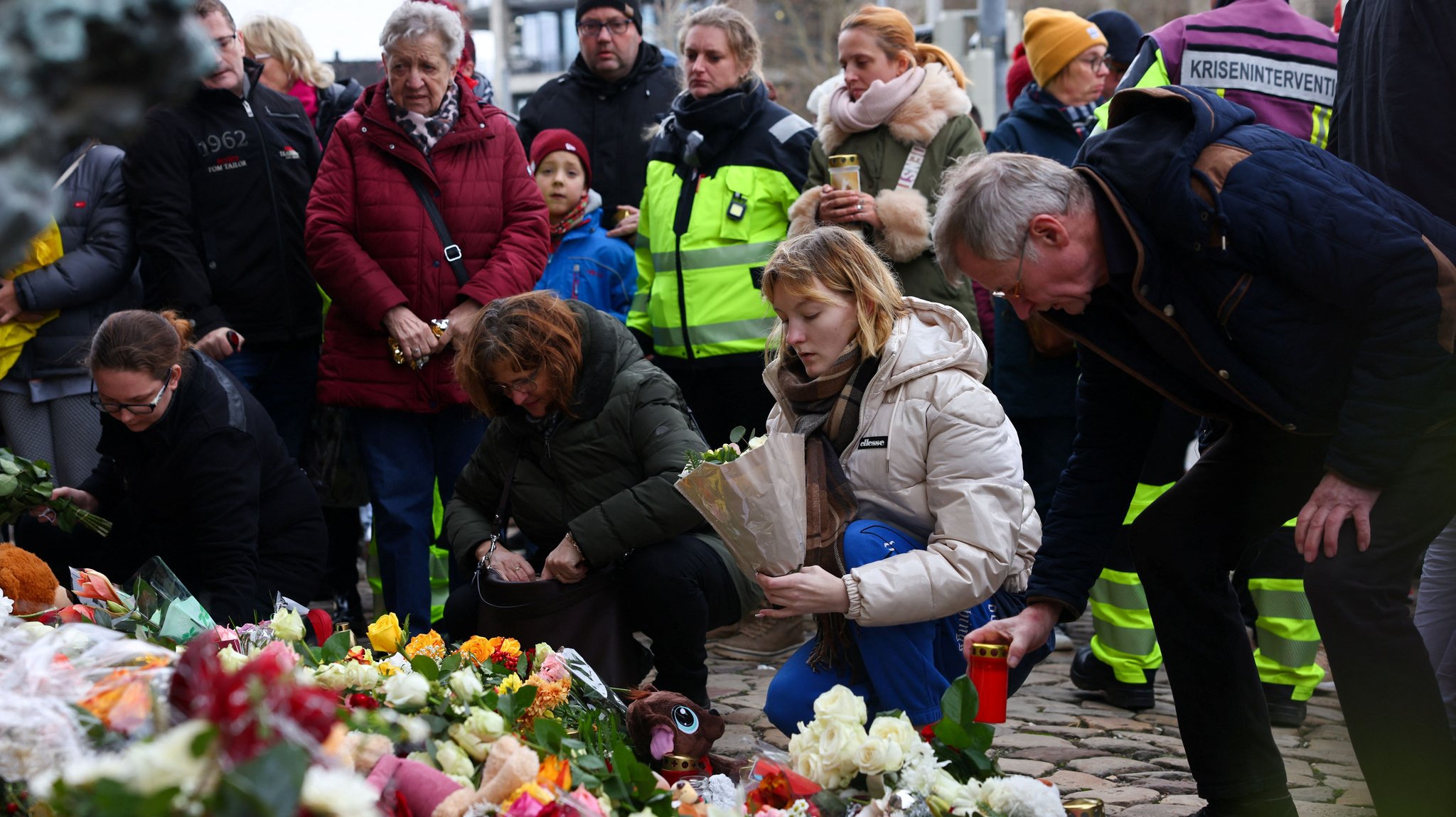 Menschen in Magdeburg legen Blumen nieder am Tatort und zünden Kerzen für die Opfer an.