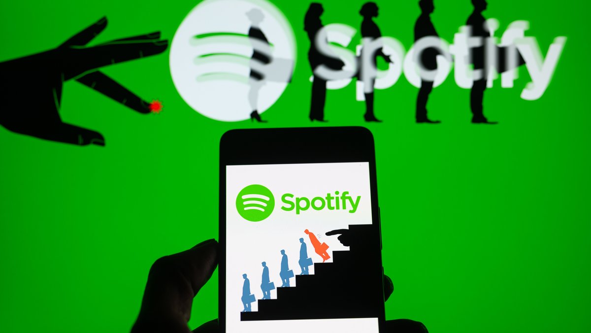 The Spotify logo is being displayed on a smartphone with a Spotify layoff icon in the background