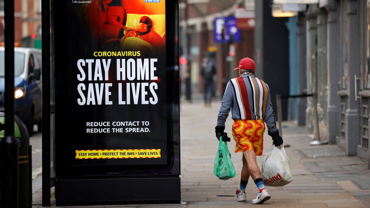 Ein Passant geht an einem Buswartehäuschen in Chinatown im Zentrum Londons am 8. Januar 2021 an einem NHS-Schild mit der Aufschrift „Stay Home, Save Lives“ (Bleiben Sie zu Hause, retten Sie Leben) vorbei, während England wegen des neuartigen Coronavirus Covid-19 zum dritten Mal eine Ausgangssperre verhängt hat. 