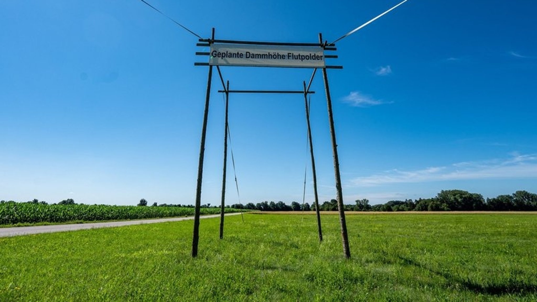 Eine große Pfahlkonstruktion in der Wiese soll die Dammhöhe für die geplanten Flutpolder vorstellbar machen.