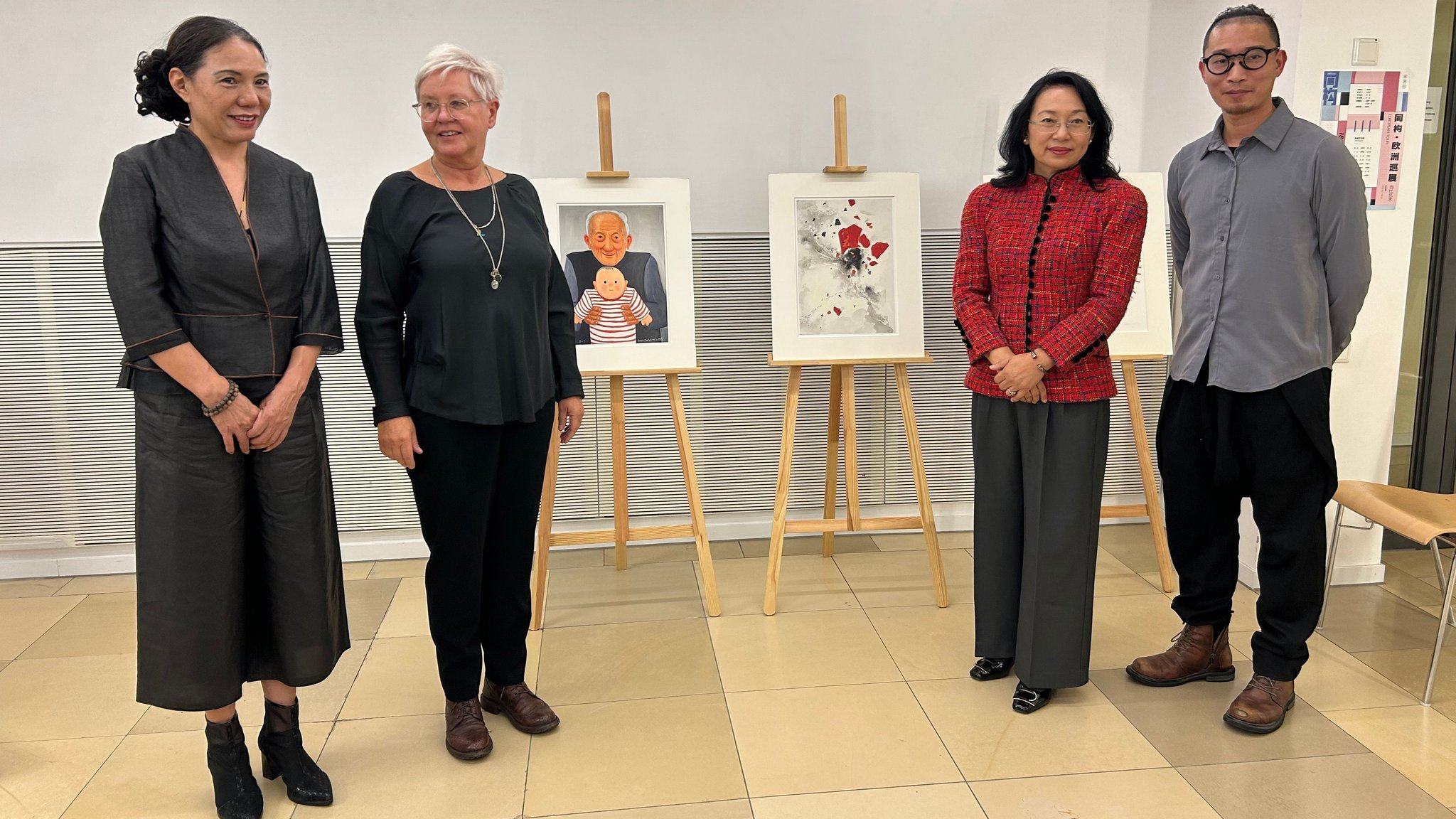 Vier Personen stehen in einem Ausstellungsraum neben zwei Bildern.