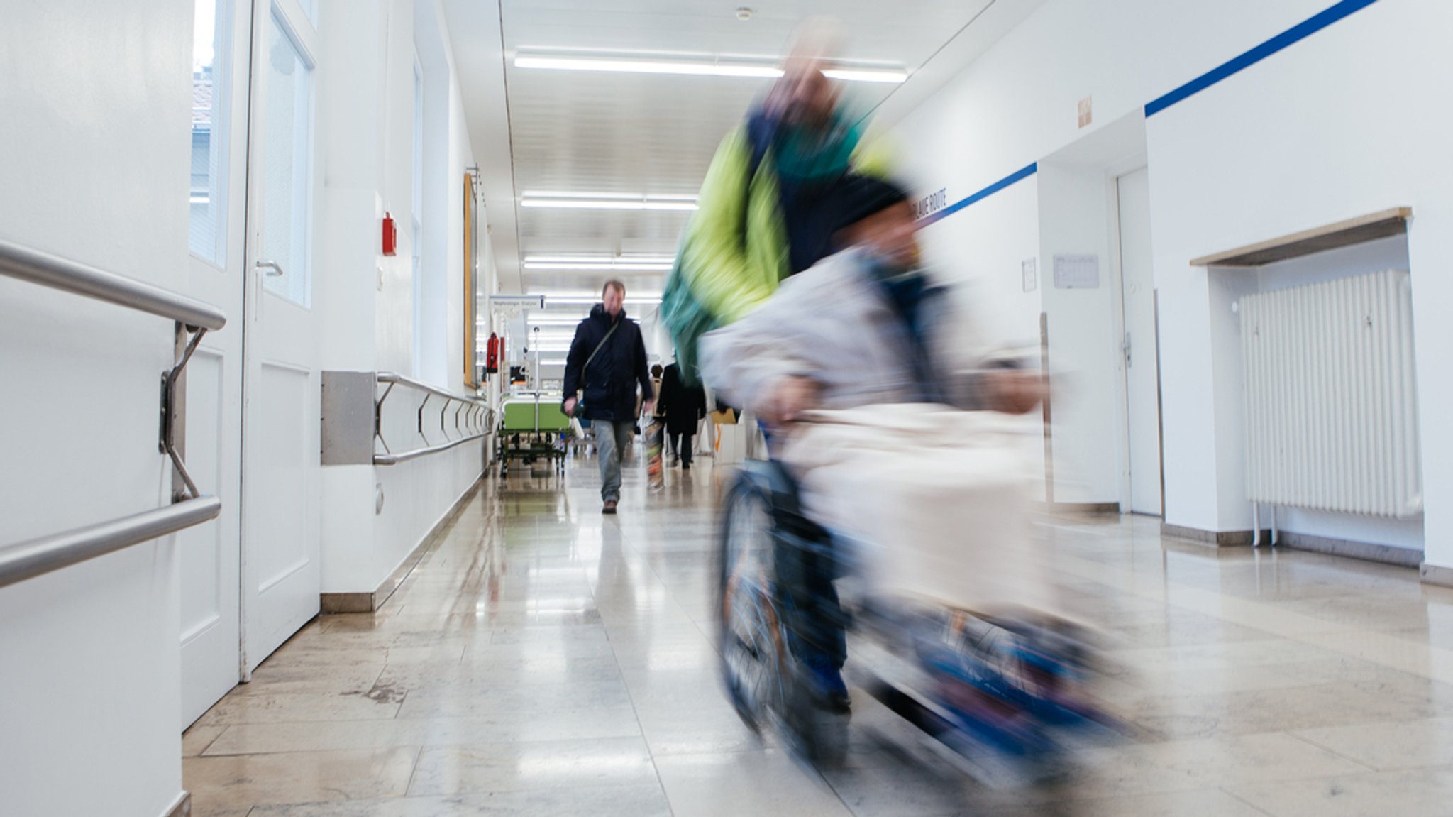 Auf dem Flur eines Krankenhauses sind Besucher und Patienten zu sehen