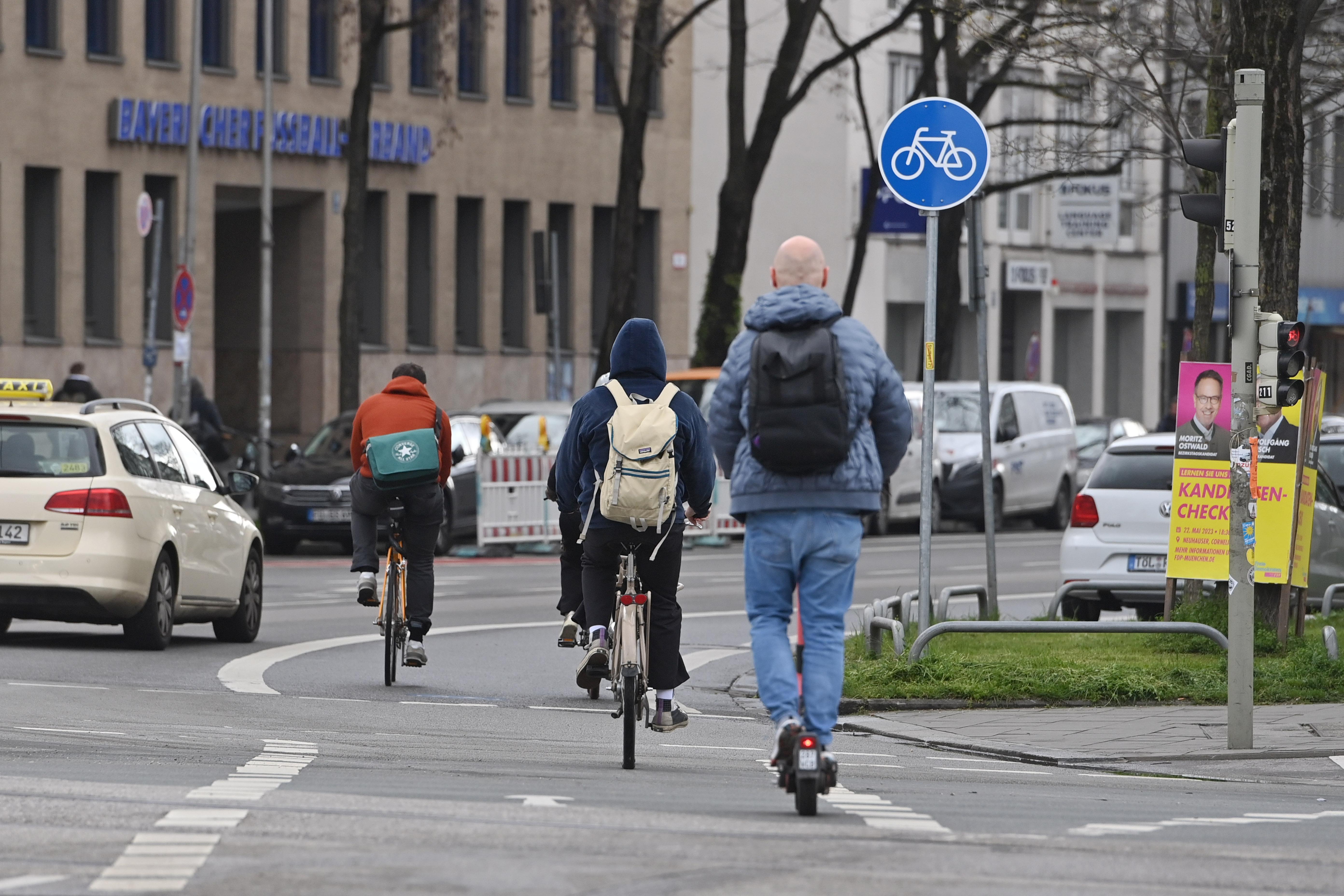 Ein Taxi, Radfahrer und ein E-Scooter-Fahrer auf einer Straße