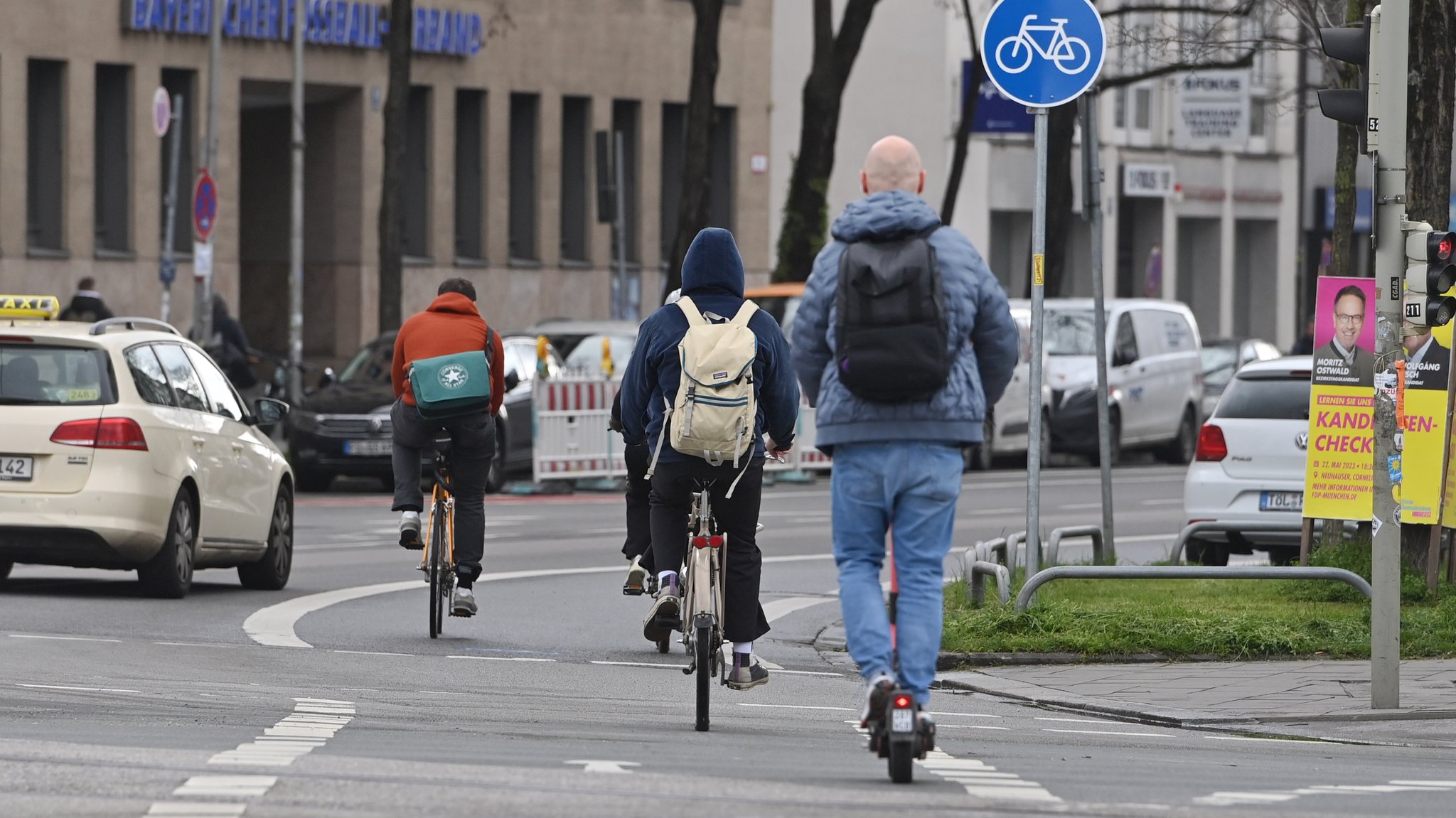 Ein Taxi, Radfahrer und ein E-Scooter-Fahrer auf einer Straße