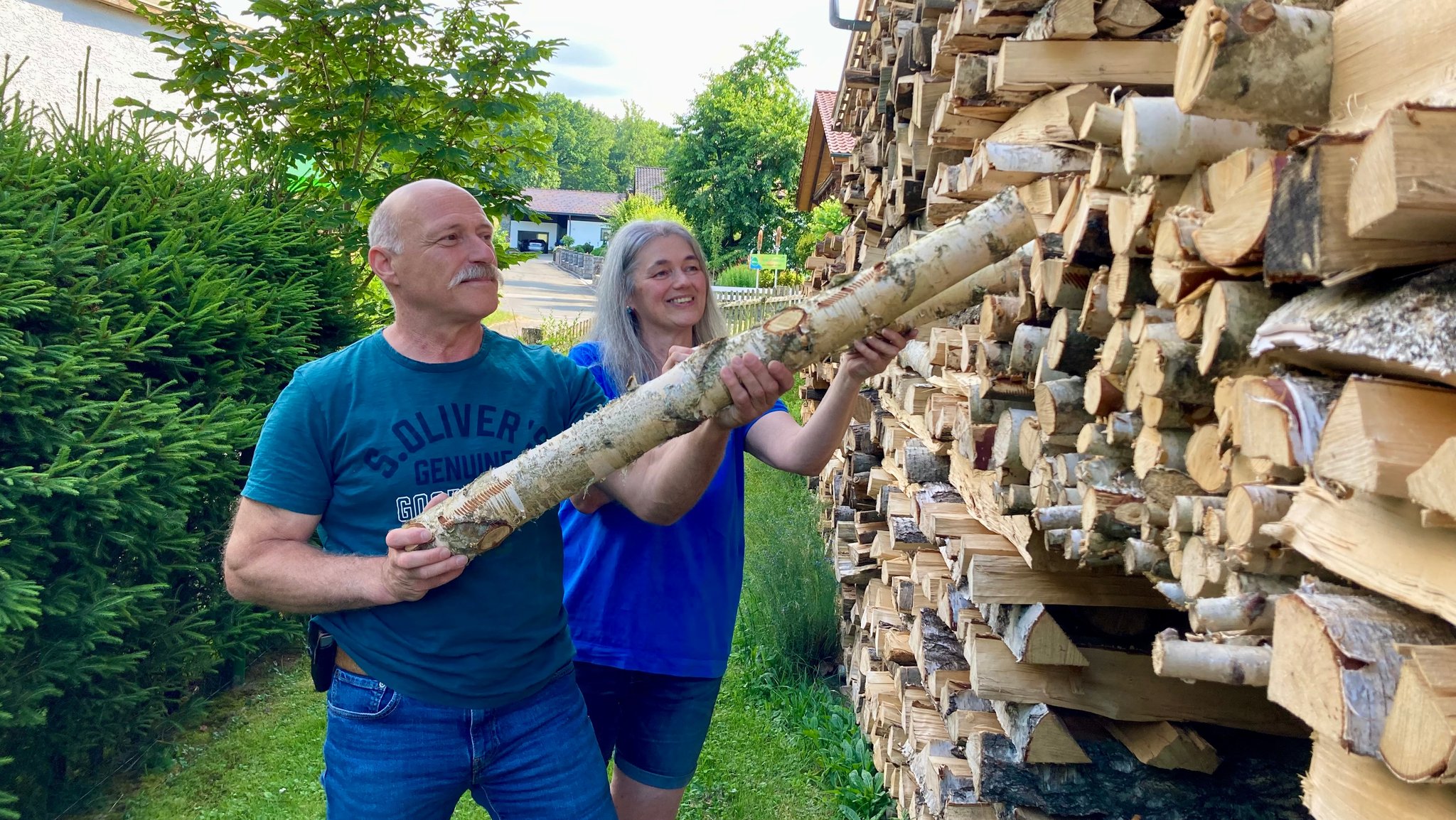 Ehepaar Klaus und Manuela Reitmeier beim Aufstapeln von Brennholz in ihrem Garten im Bayerischen Wald.