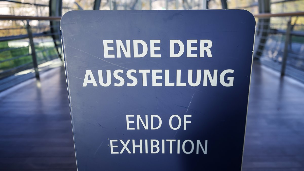 Auf einem Schild in einer Messehalle steht: "Ende der Ausstellung" (Symbolbild)