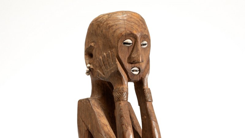 Eine geschnitzte Menschfigur aus blankem Holz mit eingelegten Muscheln als Augen und Mund | Bild: © Museum Fünf Kontinente, Foto: Nicolai Kästner Eine geschnitzte Menschfigur aus blankem Holz mit eingelegten Muscheln als Augen und Mund