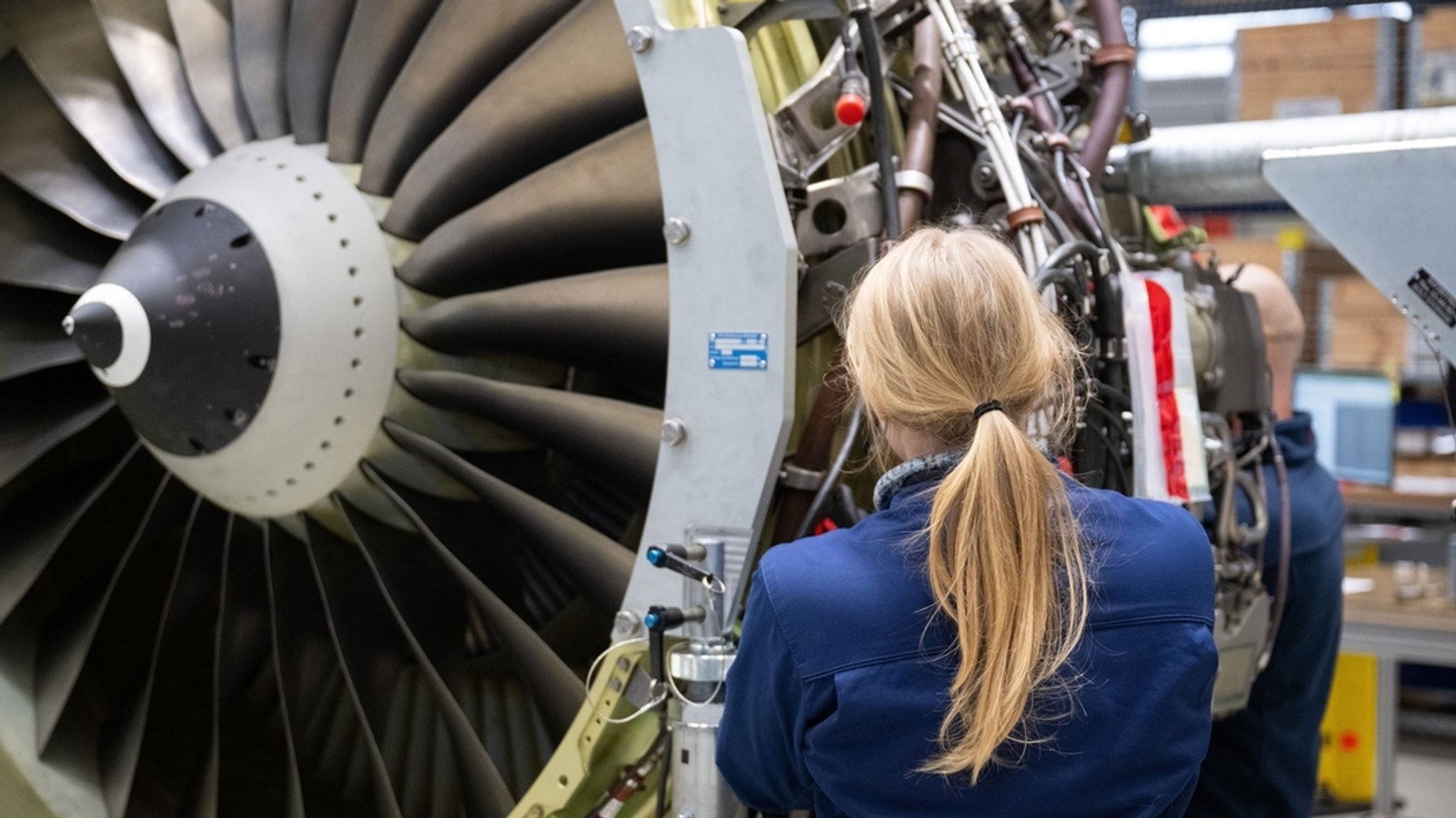 Eine Frau arbeitet in der MTU Maintenance an einem Triebwerk.
