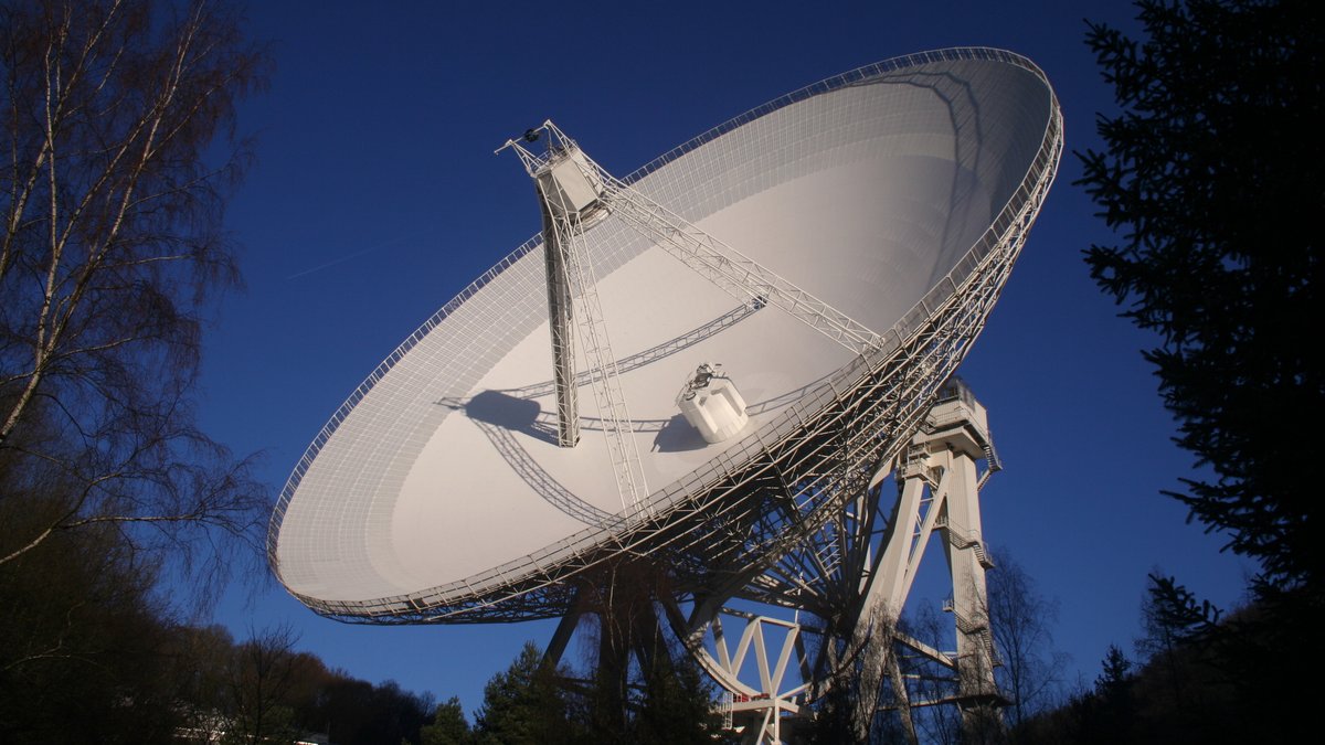 Bild zeigt ein großes, rundes Radioteleskop, welches zum Himmel gerichtet ist.