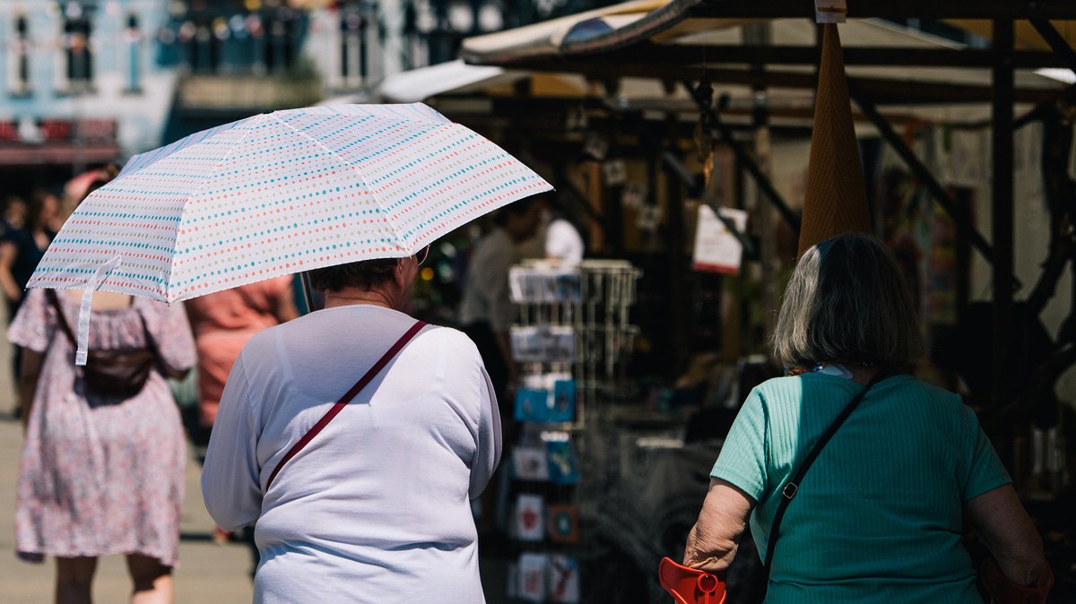 Eine Frau schützt sich mit einem Schirm vor der Sonne.