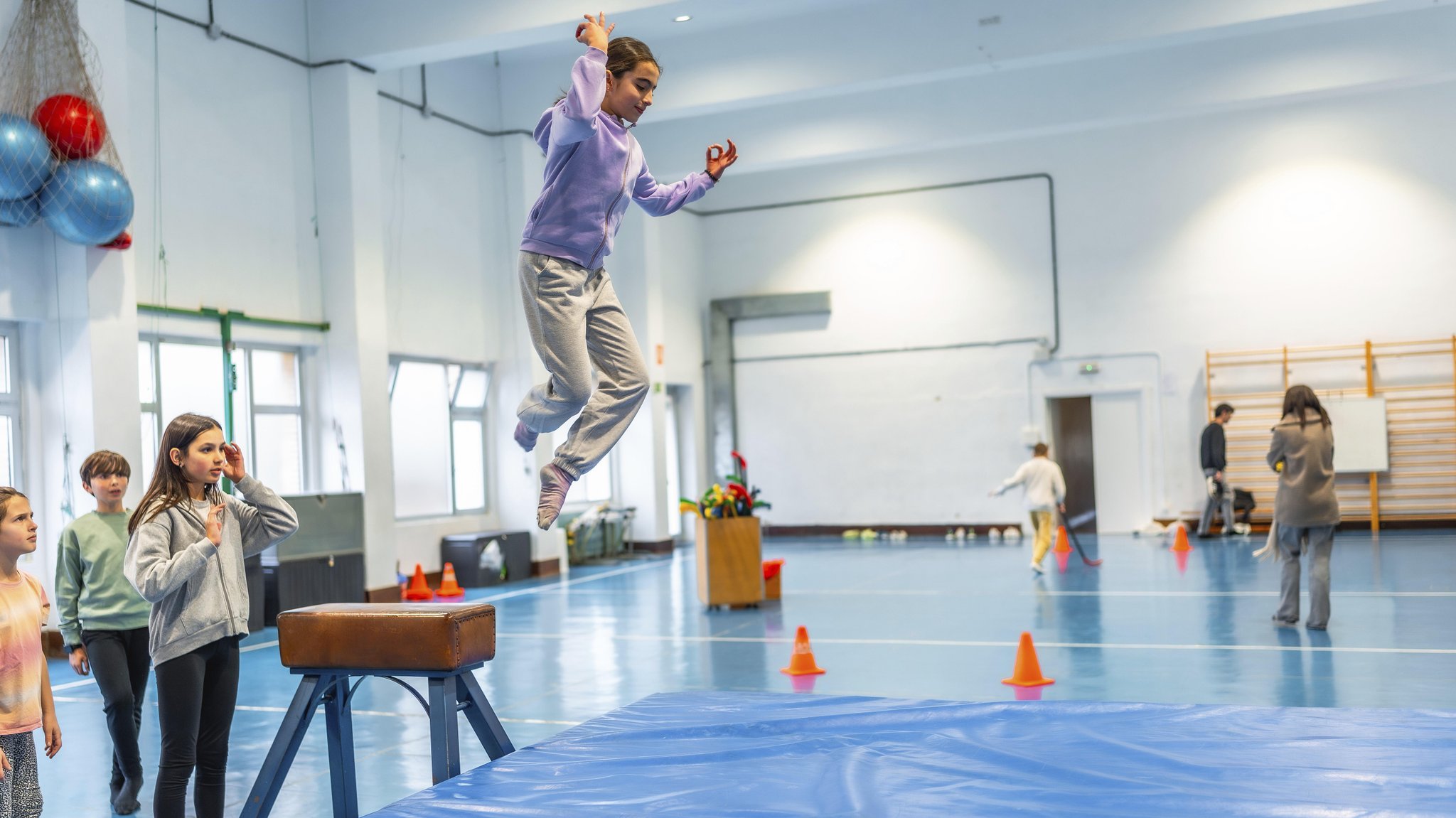 ARCHIV (09.02.2025): Schülerin beim Voltigieren im Sportunterricht, beobachtet von ihren Mitschülern und ihrer Lehrerin, demonstriert Sportlichkeit und Geschicklichkeit