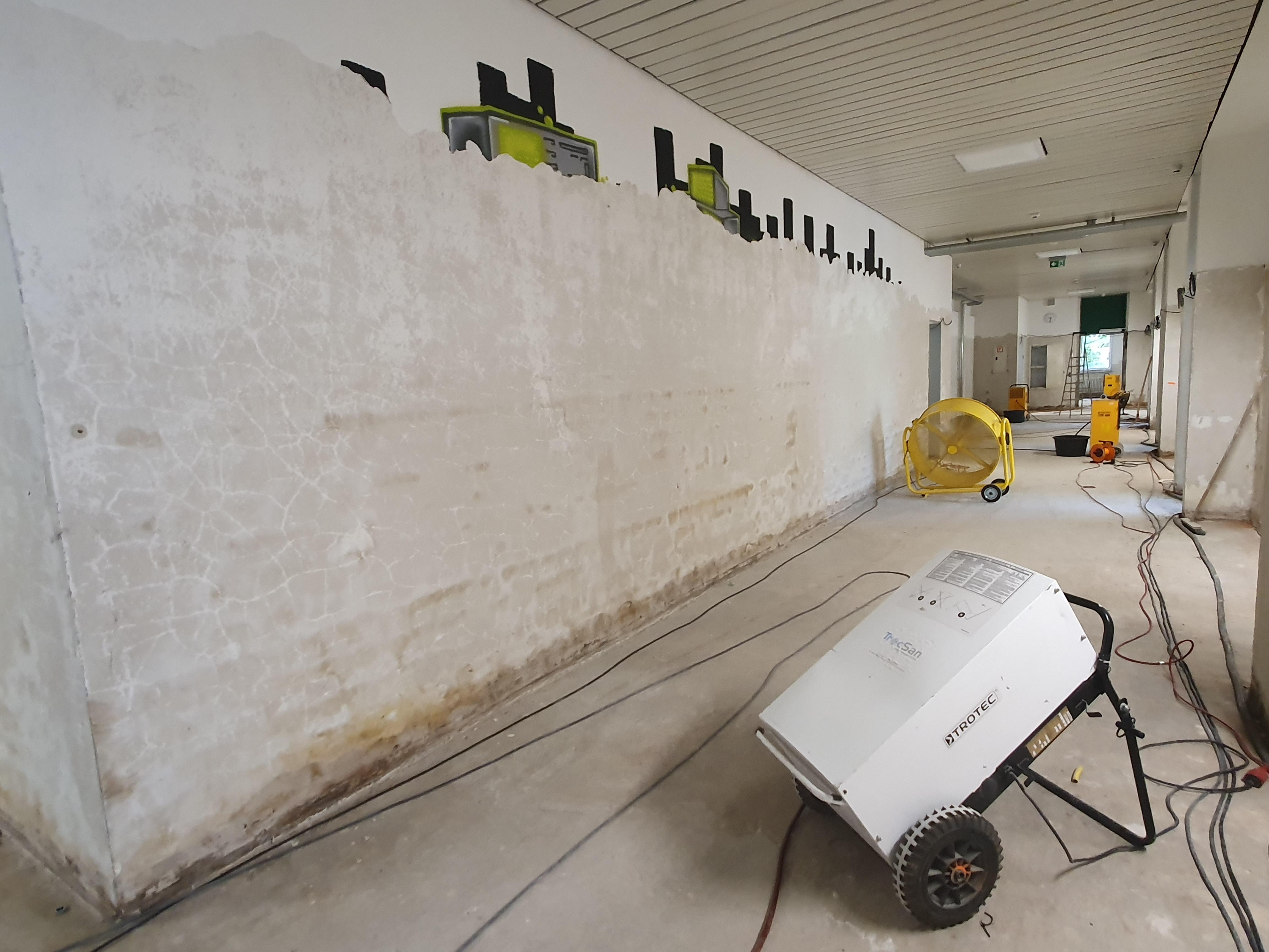 Das Wasser hat ein Graffiti an der Schulwand so gut wie verschwinden lassen. Mit Bautrocknern und Ventilatoren sollen die Räume trocken werden.