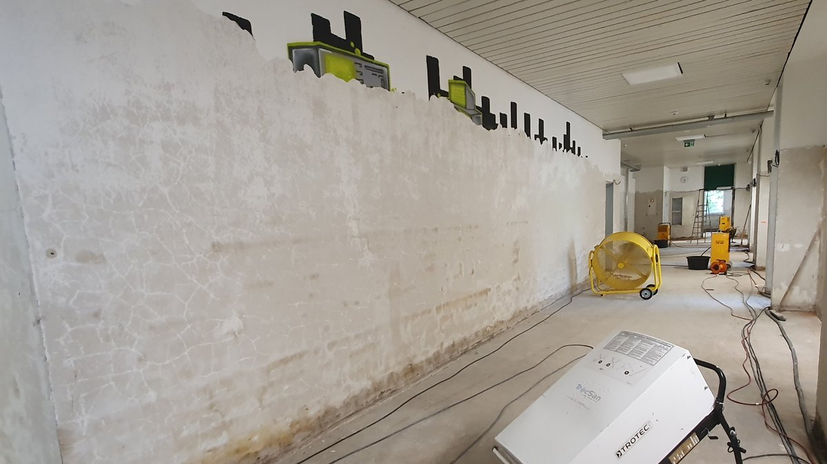 Das Wasser hat ein Graffiti an der Schulwand so gut wie verschwinden lassen. Mit Bautrocknern und Ventilatoren sollen die Räume trocken werden.