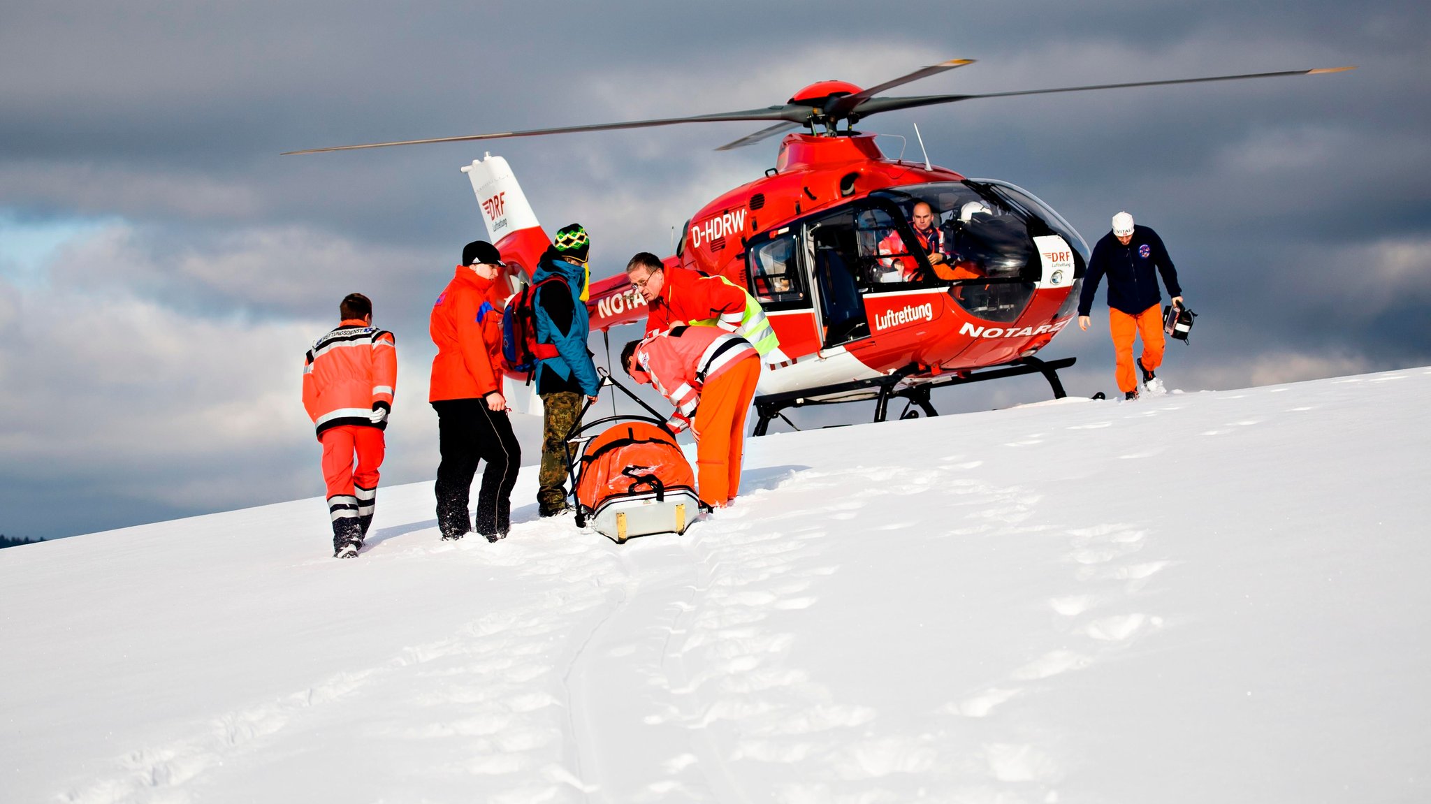 Die Besatzung eines Rettungshubschraubers vor dem Transport eines Patienten auf einem Skihang