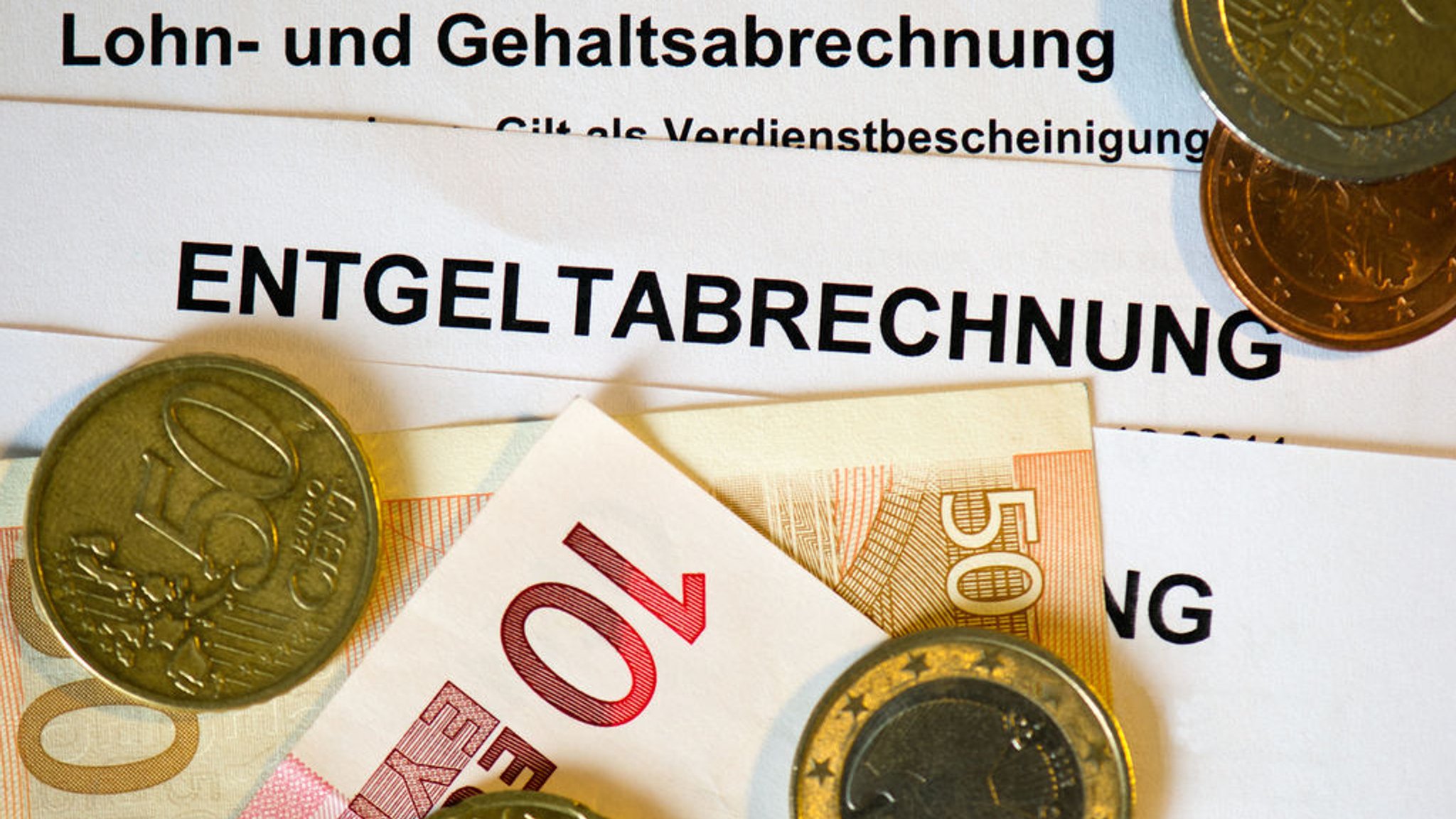 Archiv: Auf Lohn- und Gehaltsabrechnungen (Entgeltabrechnungen) liegen Euromünzen und Eurogeldscheine | Bild: dpa-Bildfunk/Arno Burgi Archiv: Auf Lohn- und Gehaltsabrechnungen (Entgeltabrechnungen) liegen Euromünzen und Eurogeldscheine