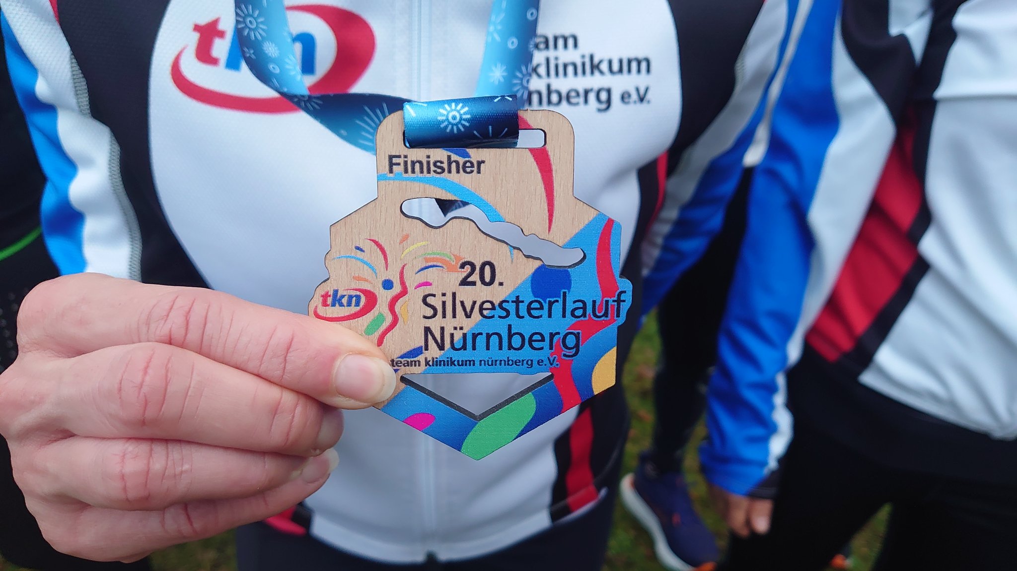 Die bunte Holz-Medaille trägt den Schriftzug "20. Silvesterlauf Nürnberg".