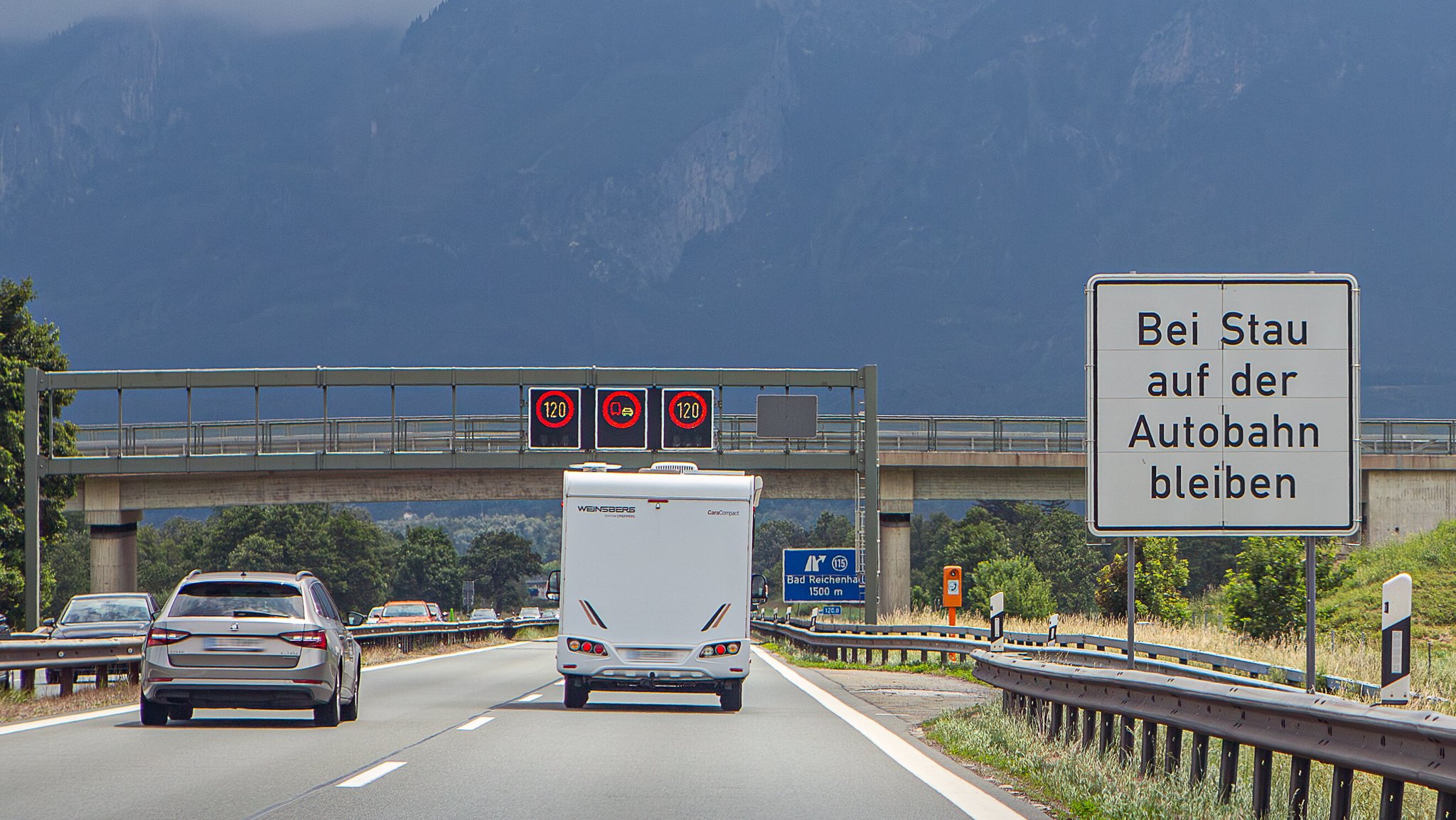 Autobahn 8 bei Bad Reichenhall - ein PKW und ein Wohnmobil sind von hinten zu sehen , kurz vor der Ausfahrt Bad Reichenhall. Auf einem Schild steht: "Bei Stau auf der Autobahn bleiben". | Bild: picture alliance / Goldmann | Goldmann Autobahn 8 bei Bad Reichenhall - ein PKW und ein Wohnmobil sind von hinten zu sehen , kurz vor der Ausfahrt Bad Reichenhall. Auf einem Schild steht: "Bei Stau auf der Autobahn bleiben".