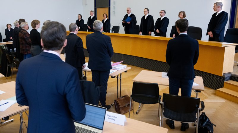 Der Bayerische Verfassungsgerichtshof unter Vorsitz von Hans-Joachim Heßler (M) steht vor der Urteilsverkündung im Gerichtssaal. Das Gericht verkündet die Entscheidung über Klagen gegen das bayerische Polizeiaufgabengesetz. | Bild: picture alliance/dpa | Sven Hoppe Der Bayerische Verfassungsgerichtshof unter Vorsitz von Hans-Joachim Heßler (M) steht vor der Urteilsverkündung im Gerichtssaal. Das Gericht verkündet die Entscheidung über Klagen gegen das bayerische Polizeiaufgabengesetz.