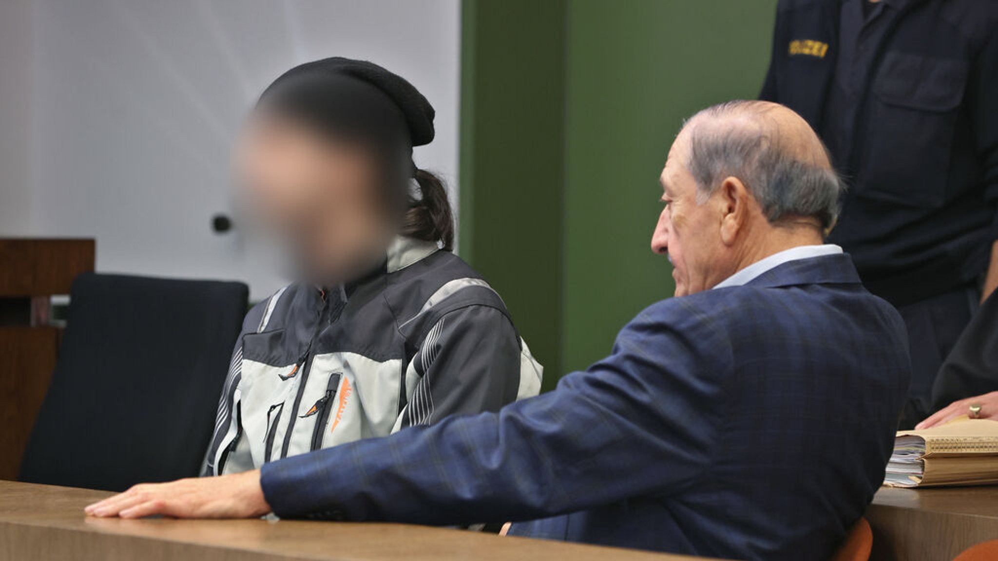 ARCHIV - 24.10.2023, Bayern, München: Ein 29-jähriger (l) Angeklagter sitzt im Landgericht neben seinem Dolmetscher auf der Anklagebank. Im wird vorgeworfen in einer Flüchtlingsunterkunft eine 21-jährige aus Rache ermordet zu haben. Foto: Karl-Josef Hildenbrand/dpa - ACHTUNG: Person(en) wurde(n) aus rechtlichen Gründen gepixelt +++ dpa-Bildfunk +++