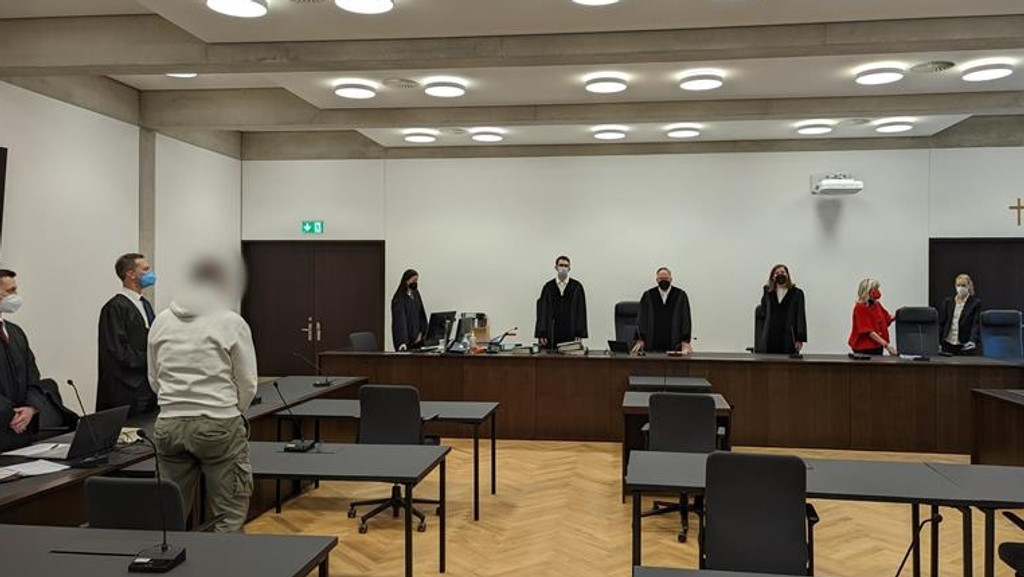Personen stehen in einem Gerichtssaal und erwarten ein Urteil