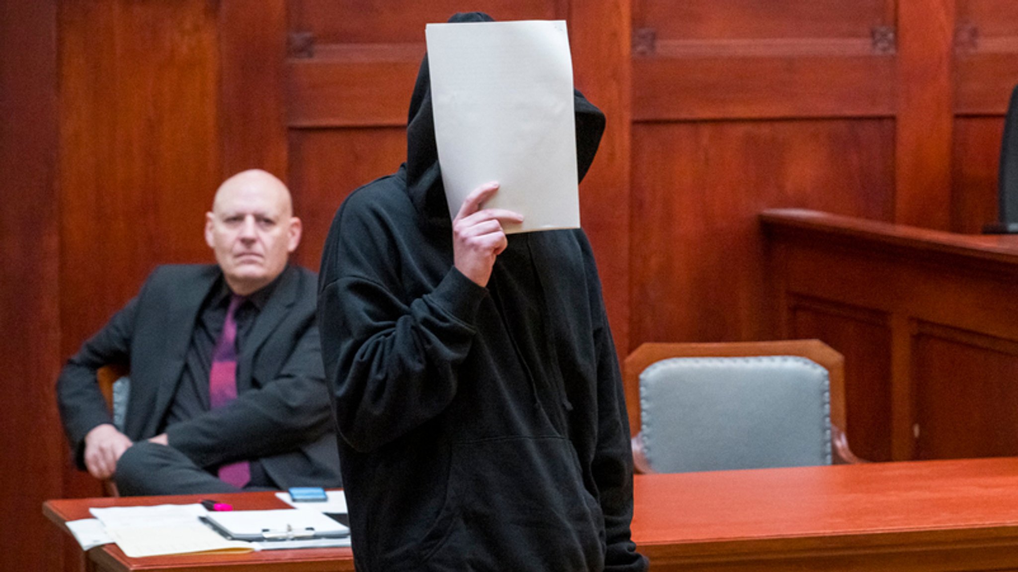 Der Angeklagte steht in einem Verhandlungssaal des Landgerichts Bayreuth. Er hält sich Zettel vor das Gesicht, sodass es nicht zu erkennen ist. | Bild: dpa-Bildfunk/Daniel Vogl Der Angeklagte steht in einem Verhandlungssaal des Landgerichts Bayreuth. Er hält sich Zettel vor das Gesicht, sodass es nicht zu erkennen ist.