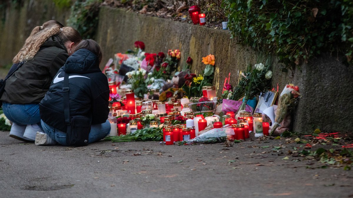 Blumen und Kerzen stehen stehen am Tatort in Illerkirchberg. Mehrere Mädchen knien davor.