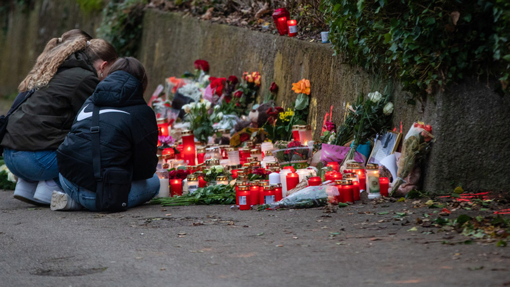 Blumen und Kerzen stehen stehen am Tatort in Illerkirchberg. Mehrere Mädchen knien davor.