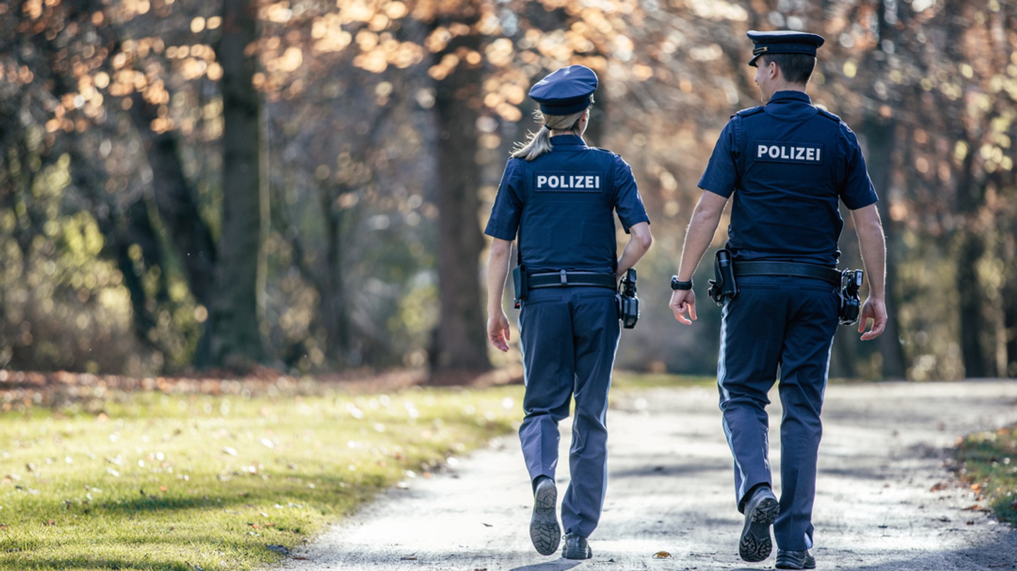 Ein Polizist und eine Polizistin gehen in einem Park auf Streife.