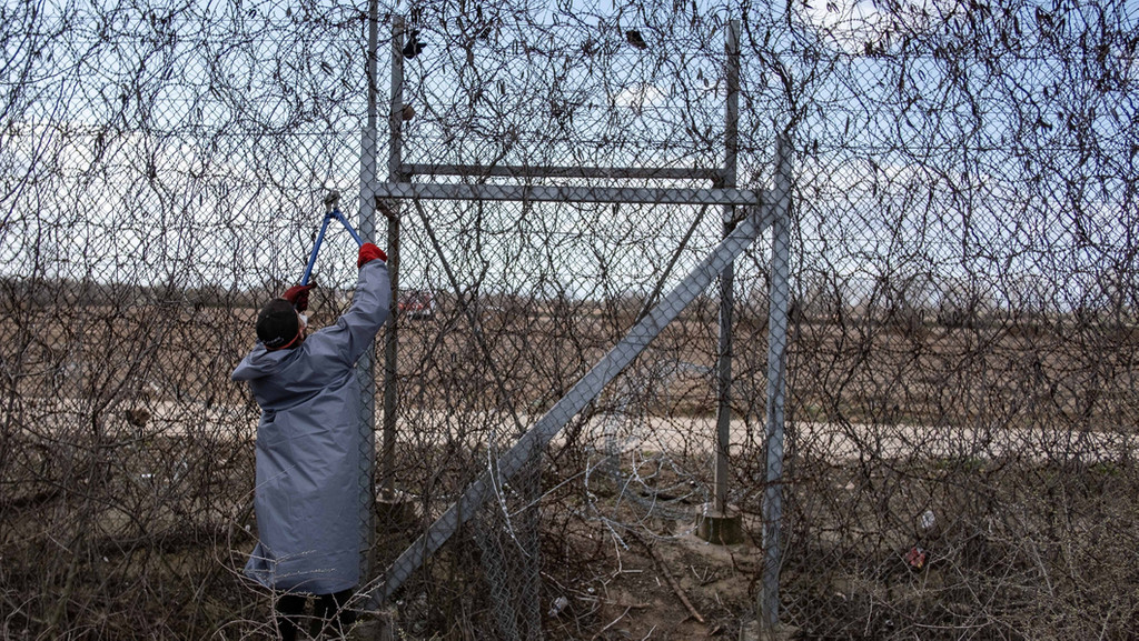Ein Migrant an der türkisch-griechischen Grenze versucht, mit einer Drahtschere den Zaun durchzuschneiden