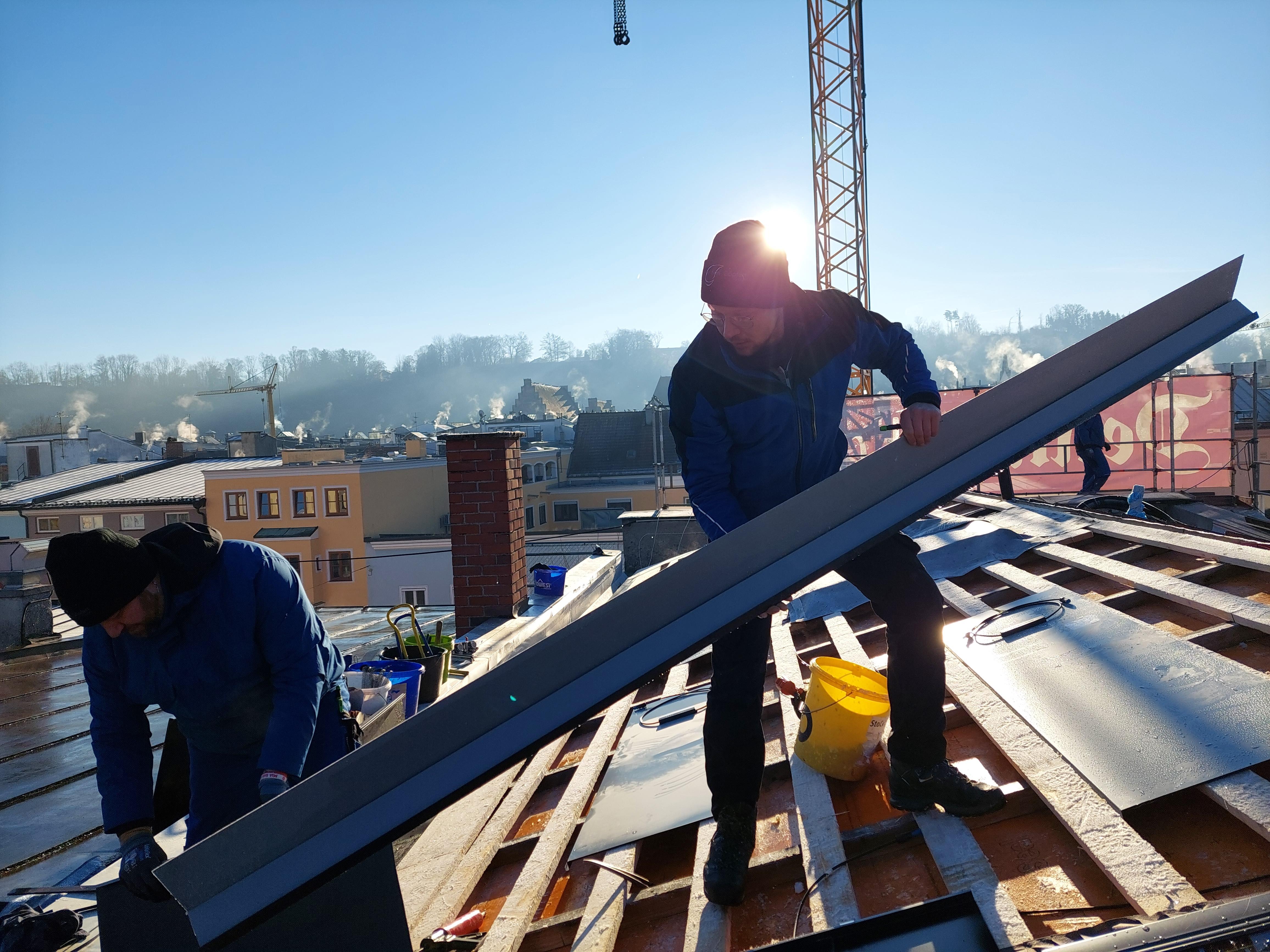 Mitarbeiter der Spenglerfirma Goepfert bei der Montage von Solarblechen auf dem Dach eines Hauses in der Altstadt von Wasserburg am Inn.