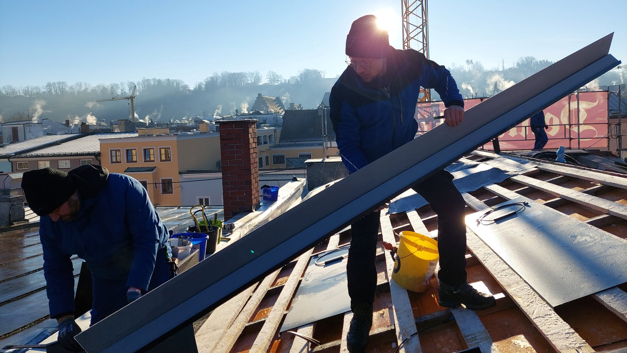 Mitarbeiter der Spenglerfirma Goepfert bei der Montage von Solarblechen auf dem Dach eines Hauses in der Altstadt von Wasserburg am Inn.