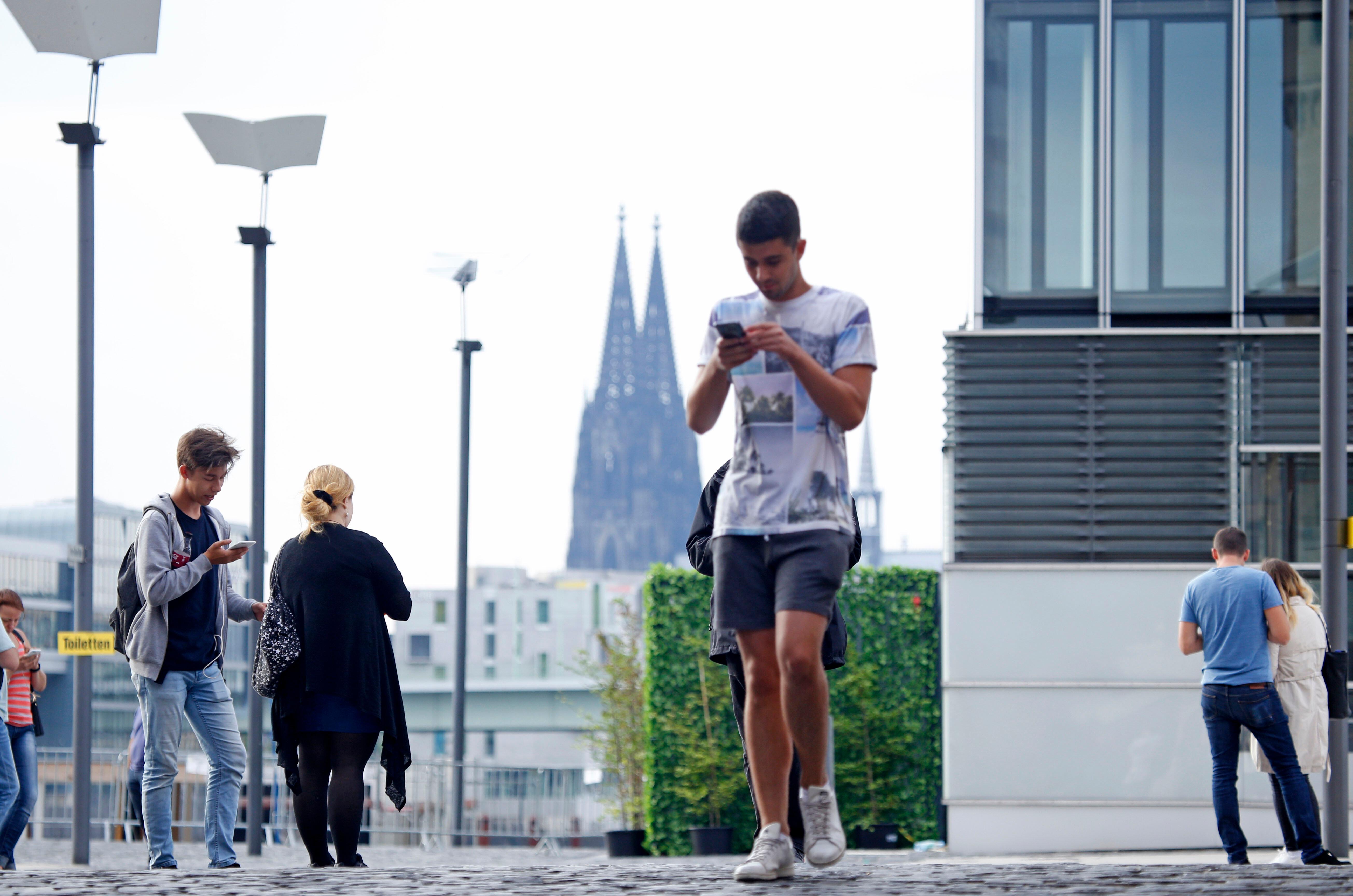 Handy-User in Köln mit Dom im Hintergrund | Bild:picture alliance / Christoph Hardt