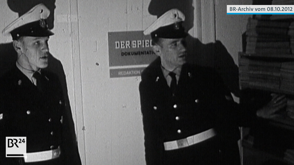 Zwei Polizisten stehen vor einer Tür mit einem Schild mit der Aufschrift  "Der Spiegel" Dokumentation