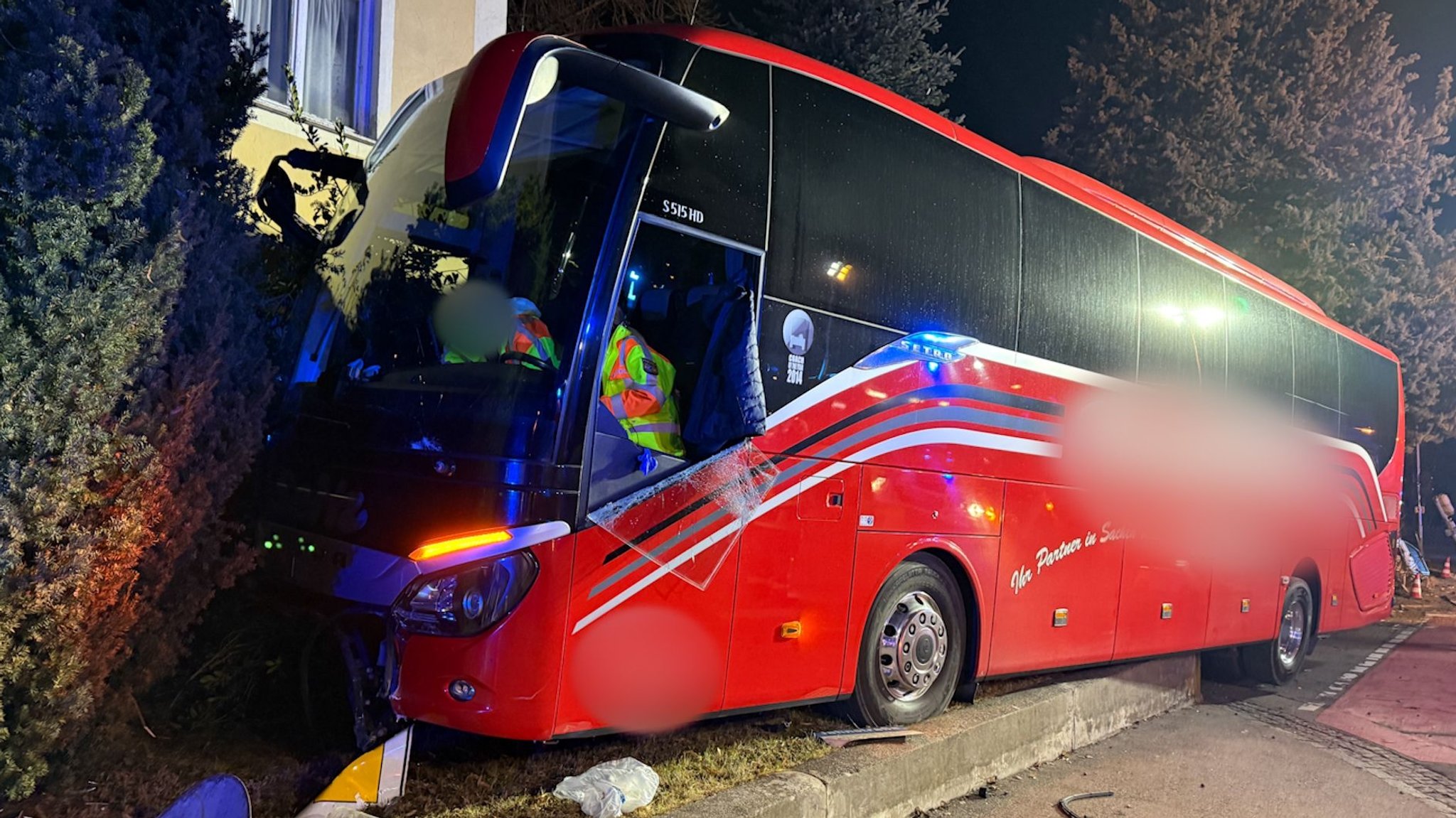 Ein verunglückter Reisebus, der in eine Hauswand geprallt war. Rettungskräfte sind im Hintergrund zu sehen.