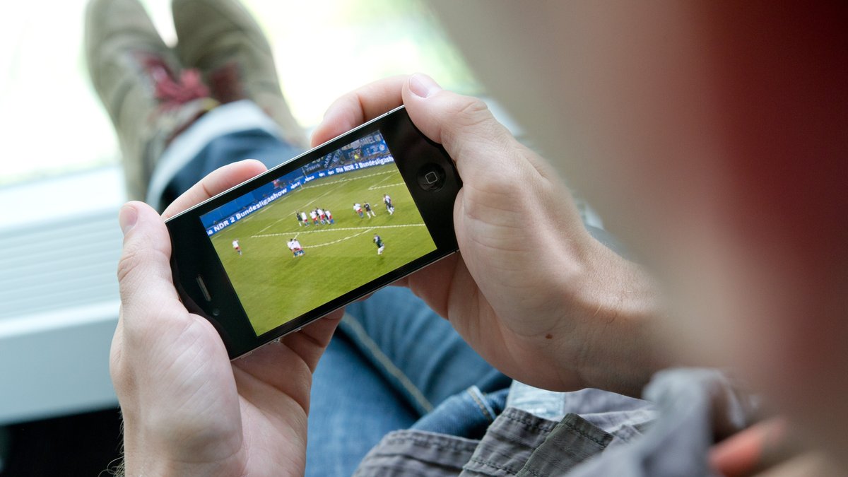 Mann schaut ein Fußballspiel auf einem Handy