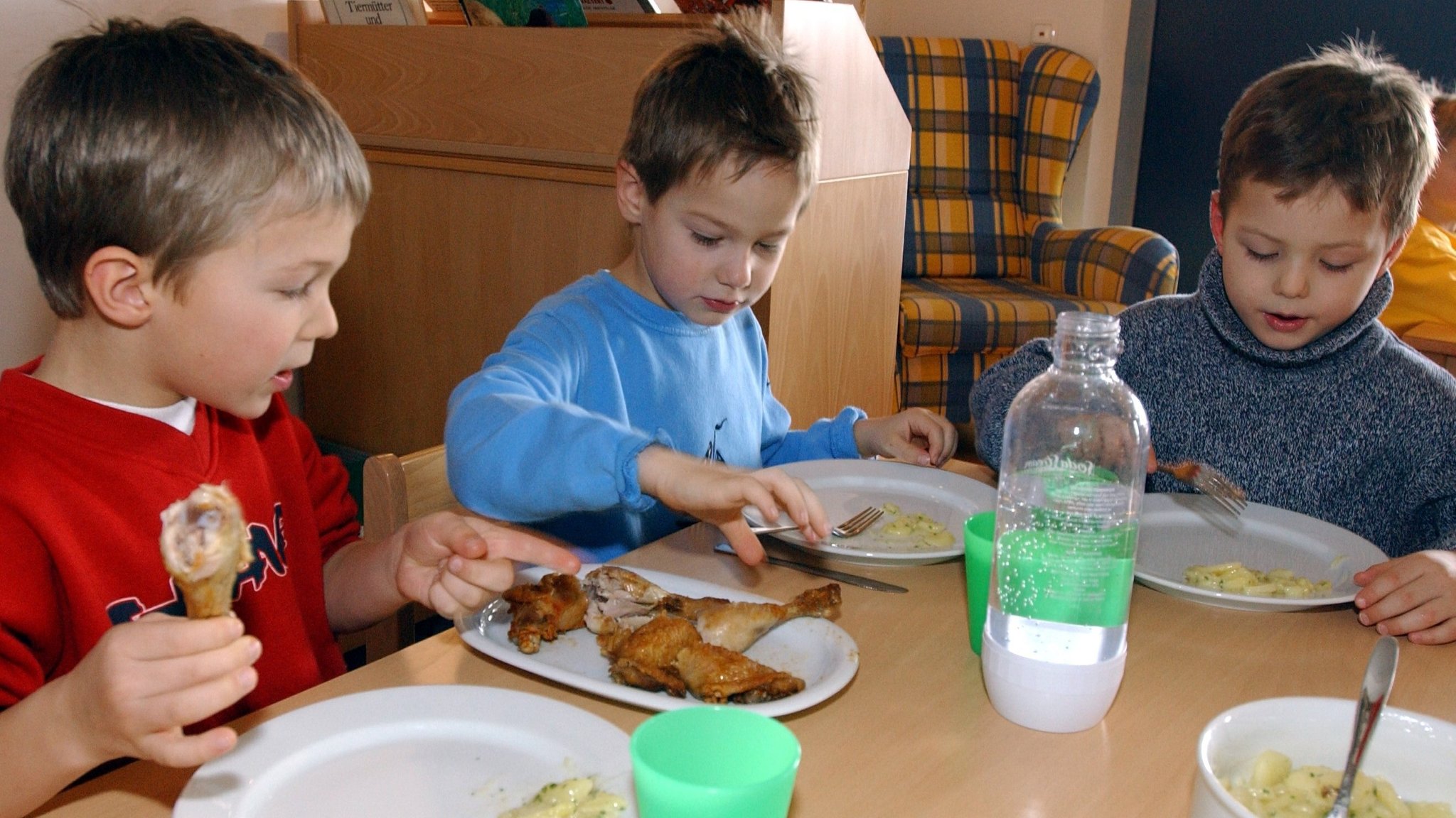 Symbolbild: Kinder essen ein Hendl im Kindergarten zu Mittag.