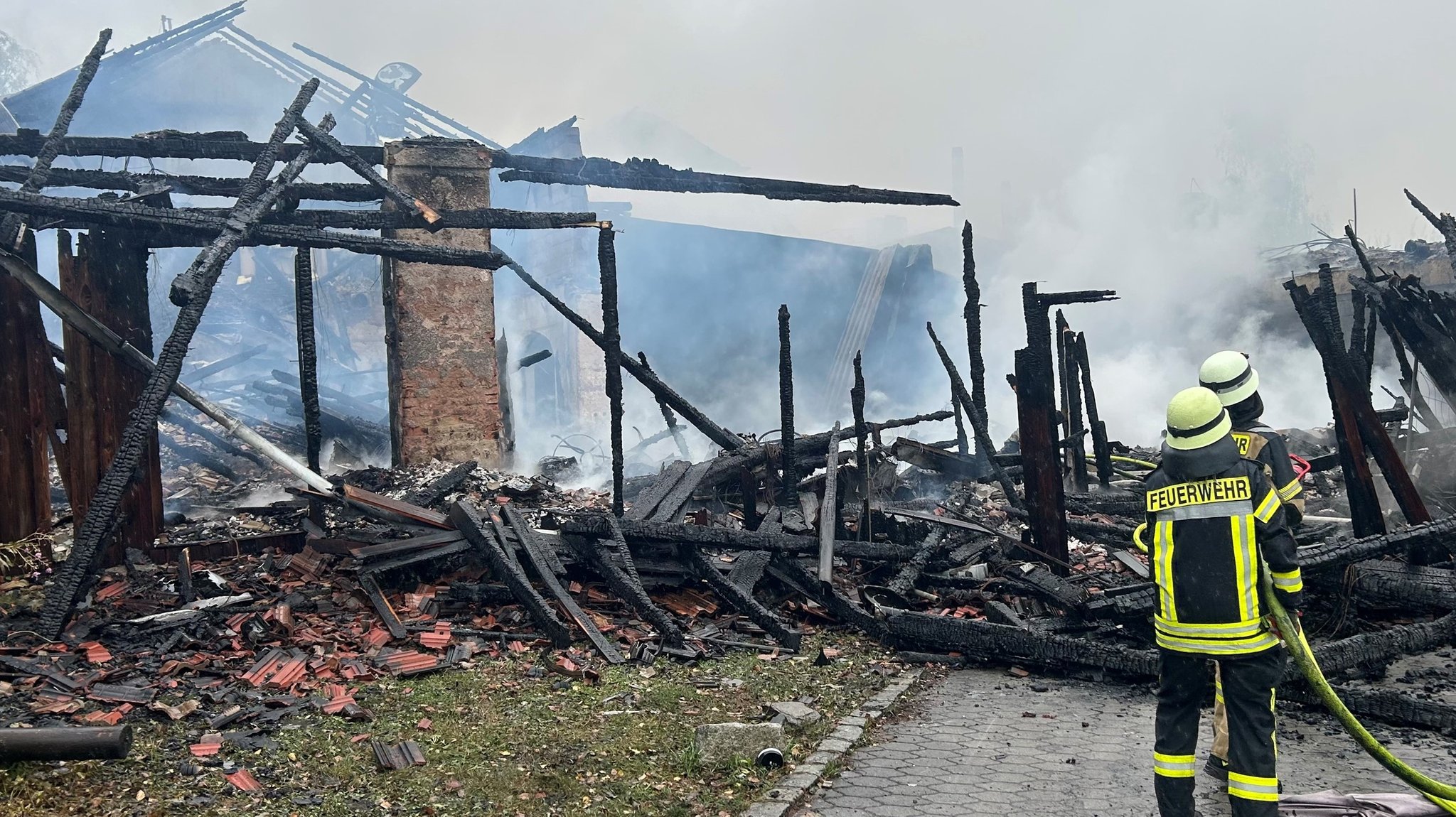 Zwei Feuerwehrleute vor der Brandruine