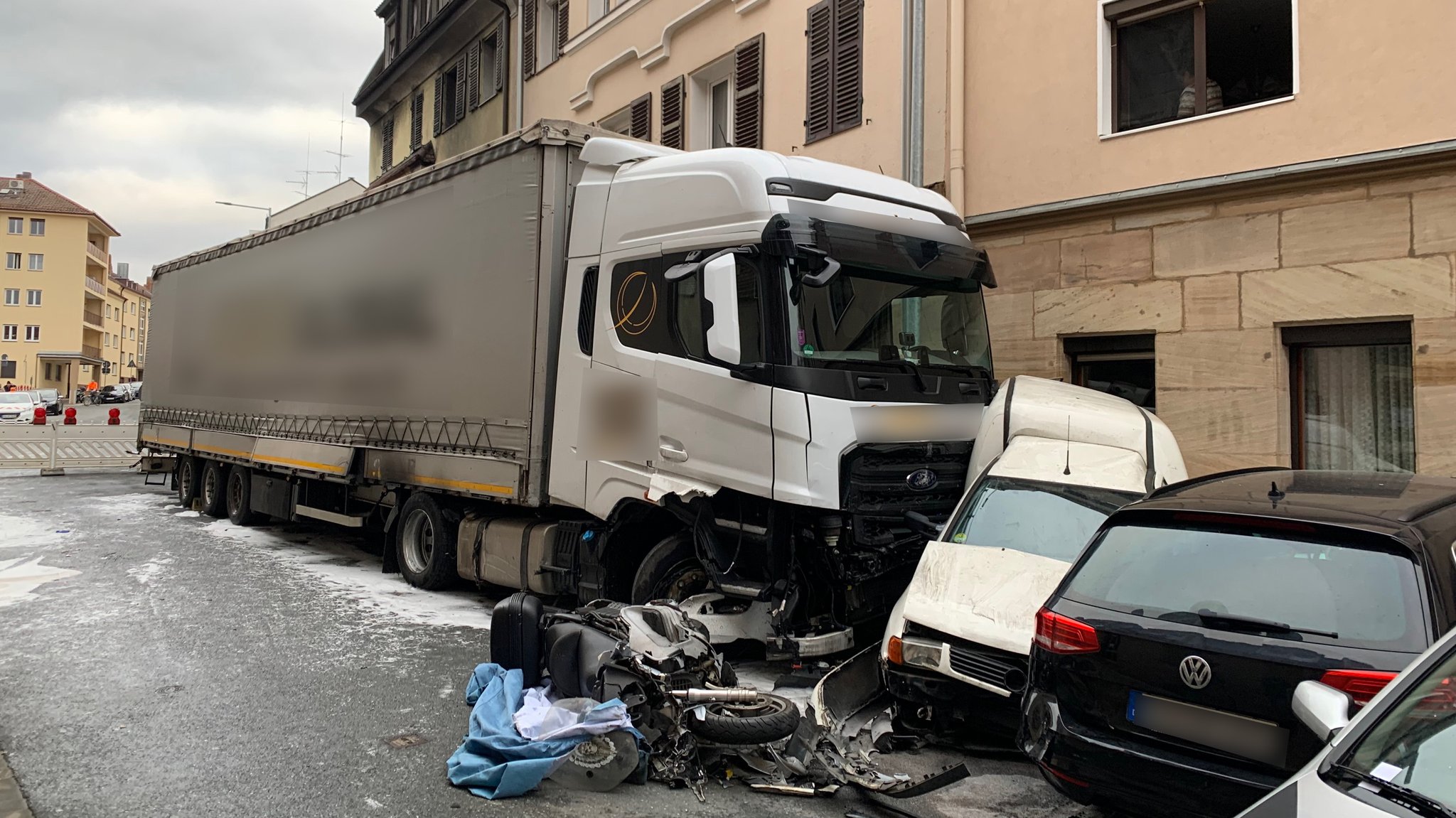 Ein ausgebrannter Lkw steht in einer Straße an einem zerstörten weißen Kastenwagen