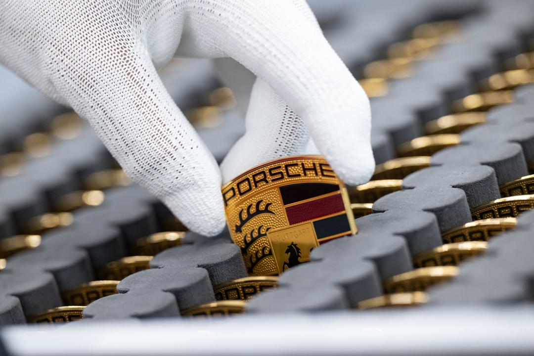  Ein Mitarbeiter der Porsche AG zeigt in einer Produktionshalle des Porsche-Stammwerks das Porsche-Logo. 