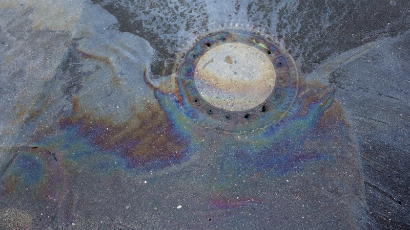 Eine mutmaßlich ölartige Flüssigkeit ist an einem Kanaldeckel einer überfluteten Straße zu sehen. Hier war der Fluss Mindel über die Ufer getreten. | Bild: picture alliance/dpa | Karl-Josef Hildenbrand Eine mutmaßlich ölartige Flüssigkeit ist an einem Kanaldeckel einer überfluteten Straße zu sehen. Hier war der Fluss Mindel über die Ufer getreten.