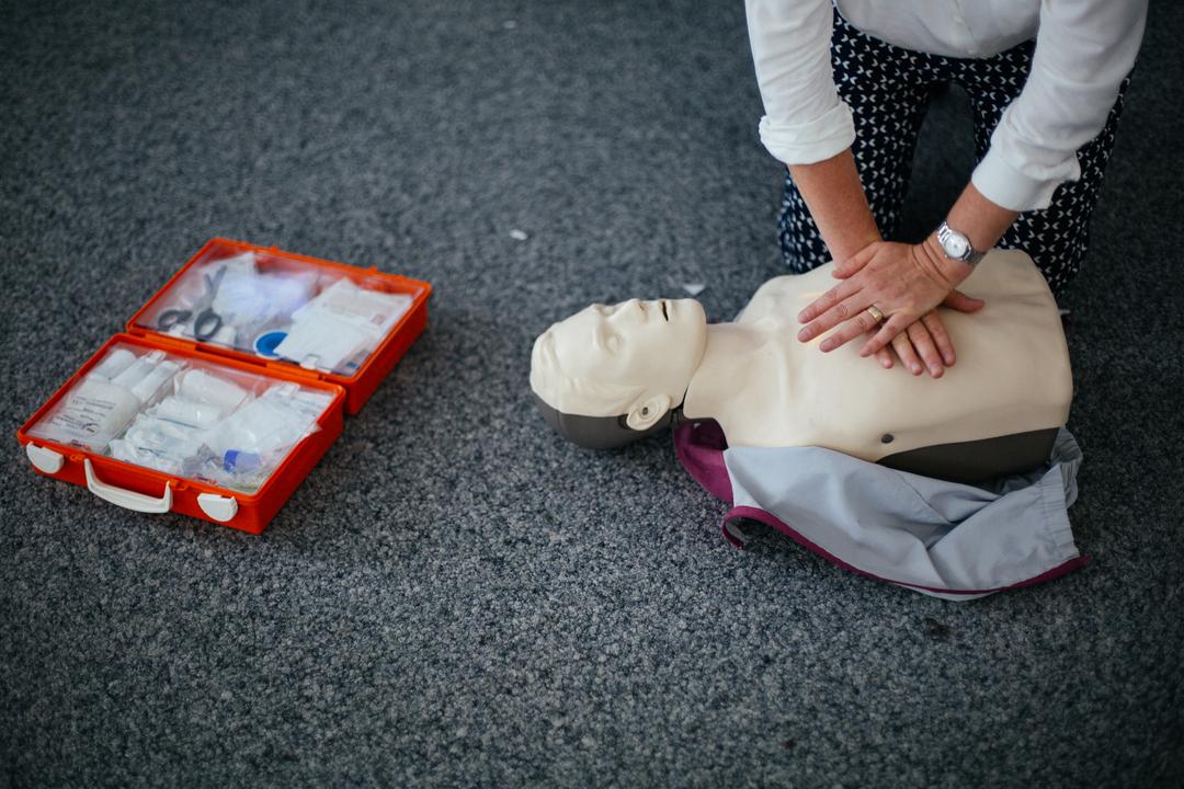 Frau übt an einer Puppe die richtige Herzdruckmassage zur Wiederbelebung.