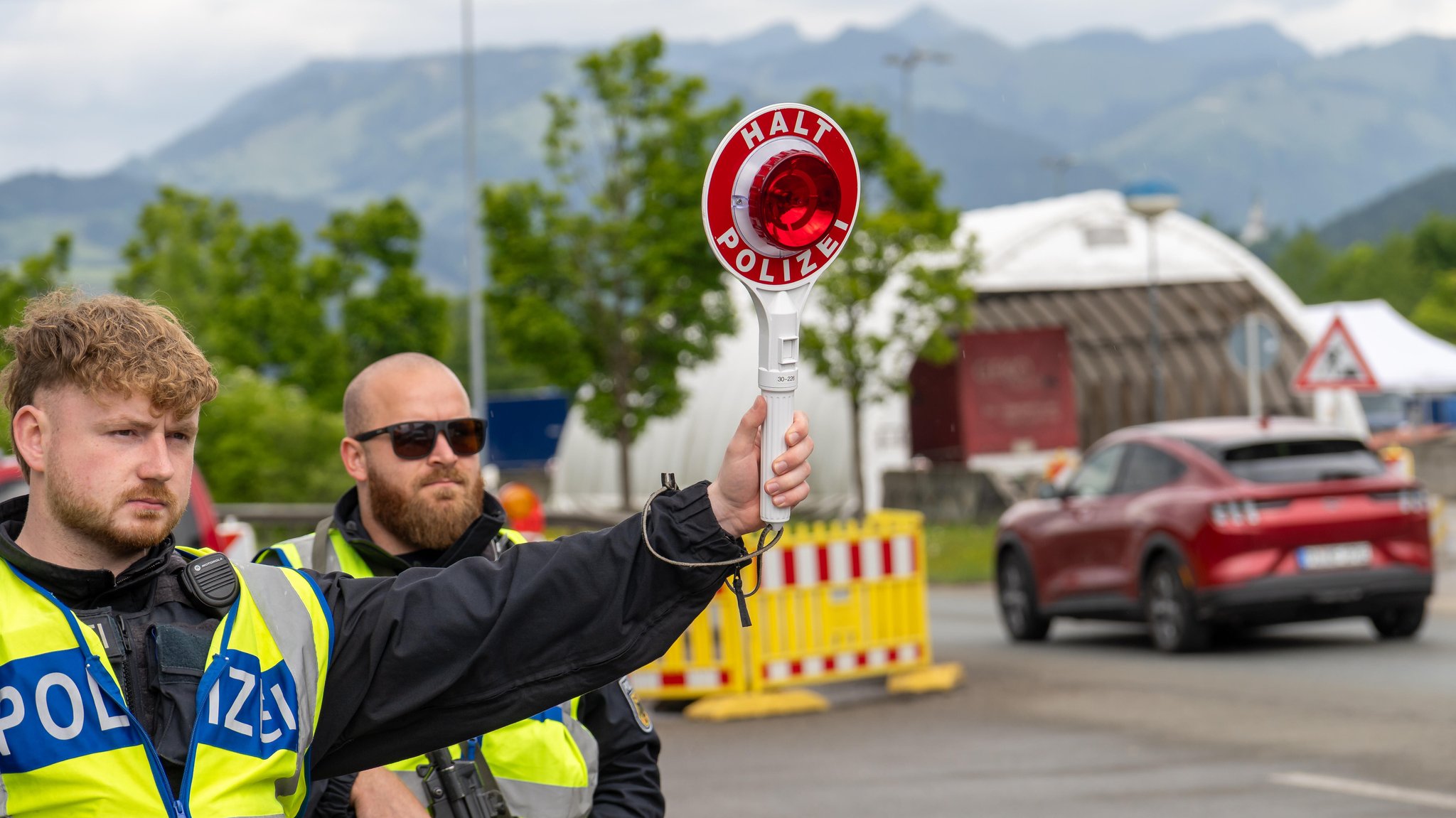 Grenzkontrolle der Bundespolizei an der Kontrollstelle Kiefersfelden, Inntal Ost, an der Autobahn A93 zwischen Deutschland und Österreich. Polizisten ziehen ein Fahrzeug aus dem Verkehr mit der Polizeikelle mit Aufschrift HALT POLIZEI | Bild: picture alliance / CHROMORANGE | Michael Bihlmayer Grenzkontrolle der Bundespolizei an der Kontrollstelle Kiefersfelden, Inntal Ost, an der Autobahn A93 zwischen Deutschland und Österreich. Polizisten ziehen ein Fahrzeug aus dem Verkehr mit der Polizeikelle mit Aufschrift HALT POLIZEI
