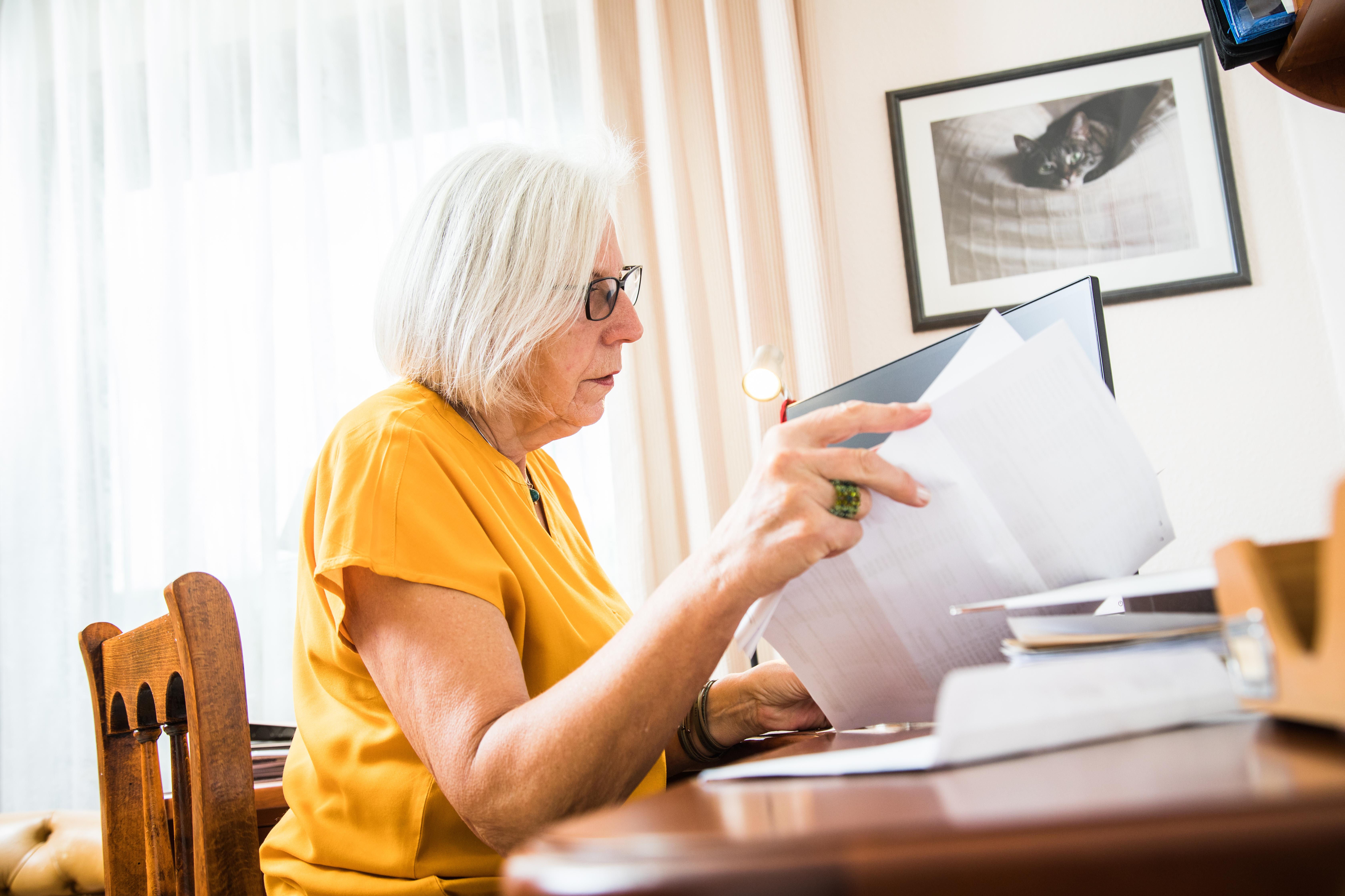 Eine Rentnerin sitzt an ihrem Schreibtisch und sortiert Belege für die Steuererklärung.