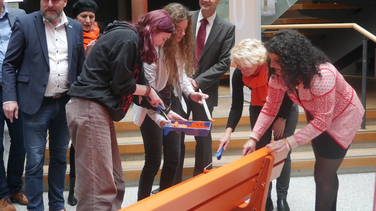 Carmen Schiller (rechts) streicht die Parkbank als Zeichen gegen Gewalt mit Schülerinnen und Schülern des Gymnasiums Veitshöchheim. 